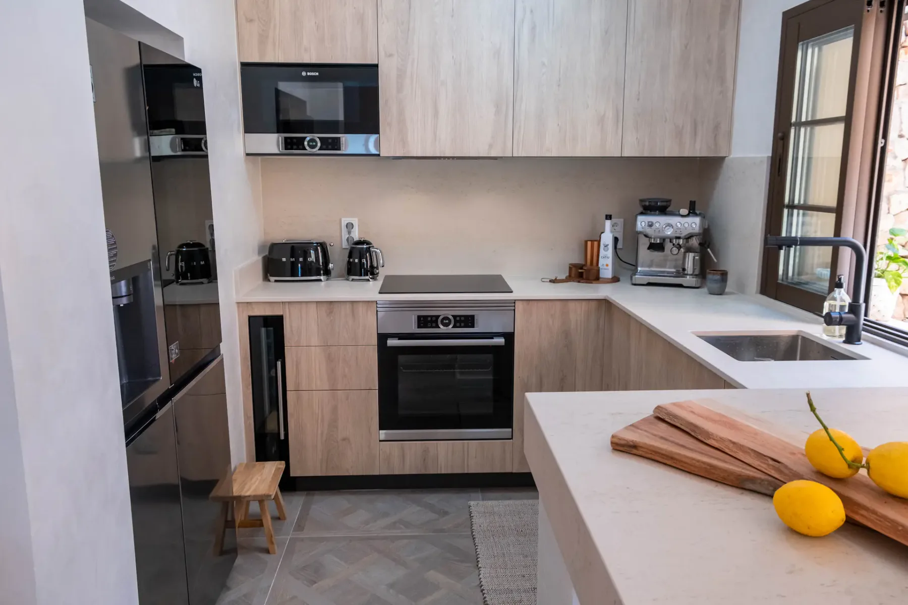 A modern kitchen with light cabinetry, built-in appliances, and a broad countertop.