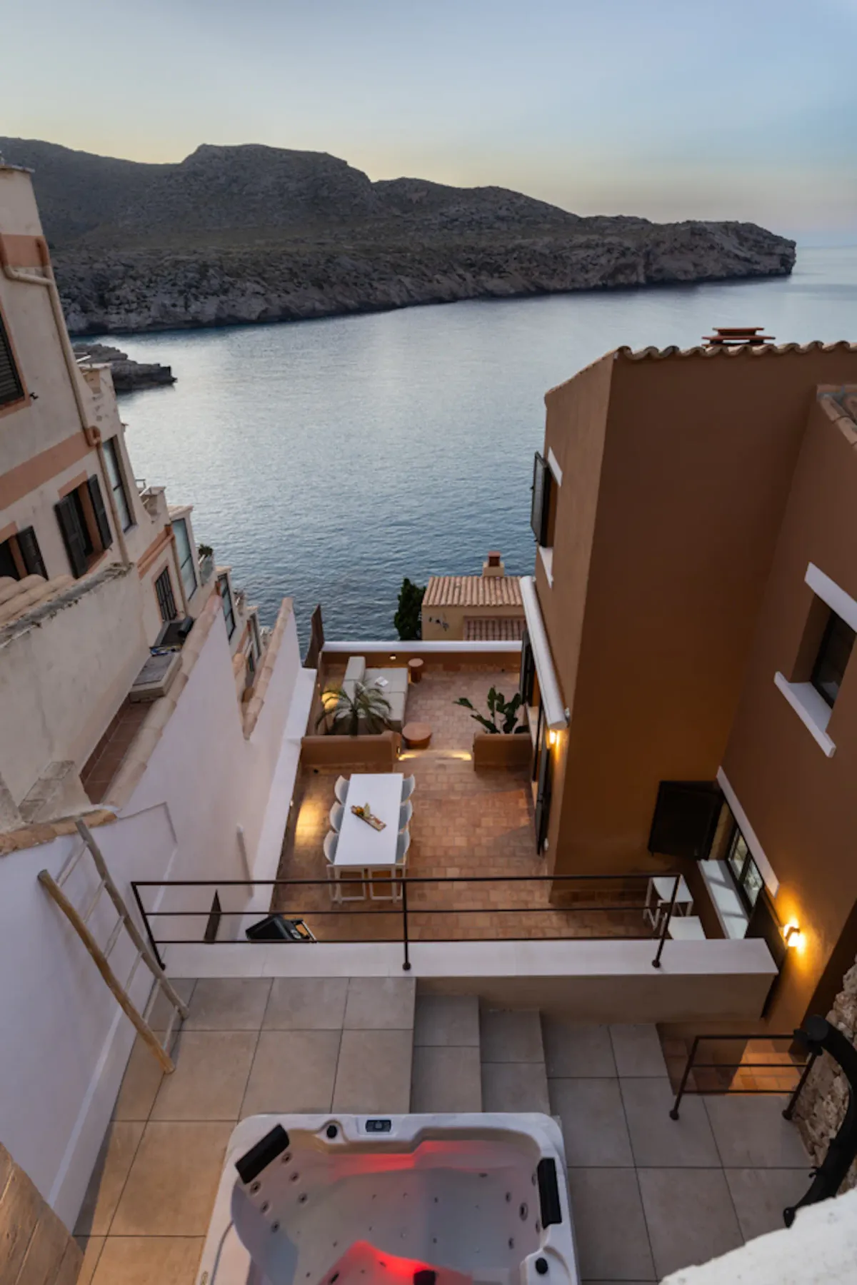A terrace with a hot tub overlooks the sea and a rocky coastline.