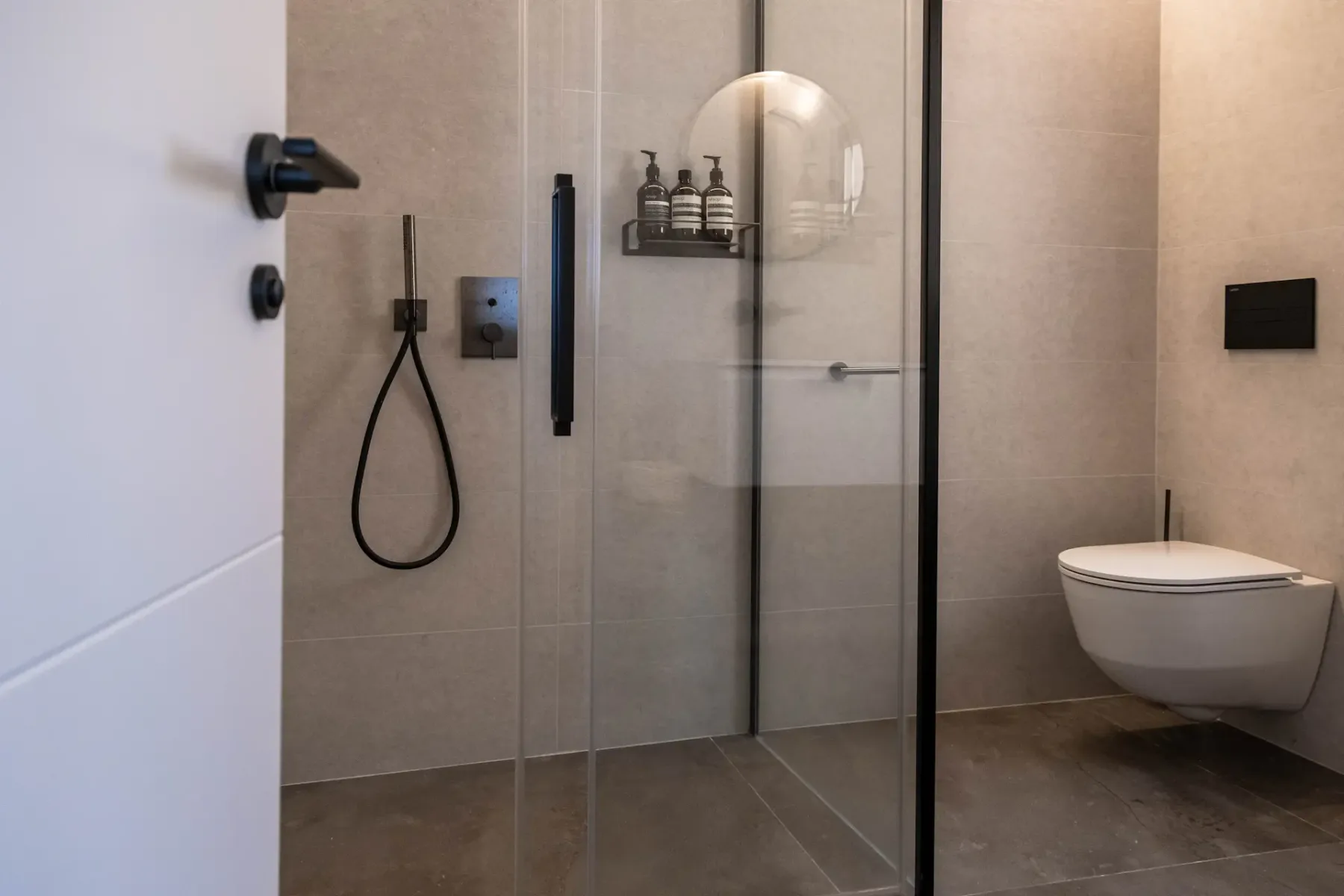 A modern bathroom with a glass shower and wall-mounted toilet.