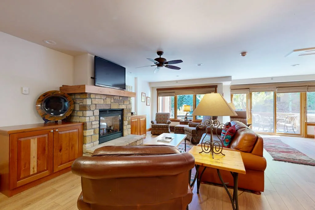 Una sala luminosa con asientos de cuero, una chimenea y grandes ventanas.