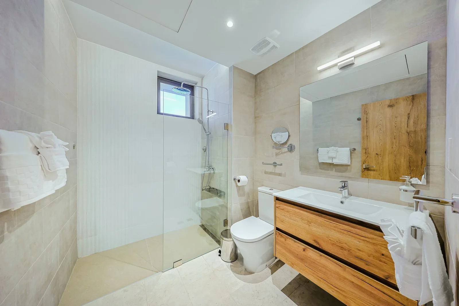 Step into your bright, modern bathroom with sleek tile, a glass-enclosed rainfall shower, and warm wood accents that make every morning feel like a spa experience.