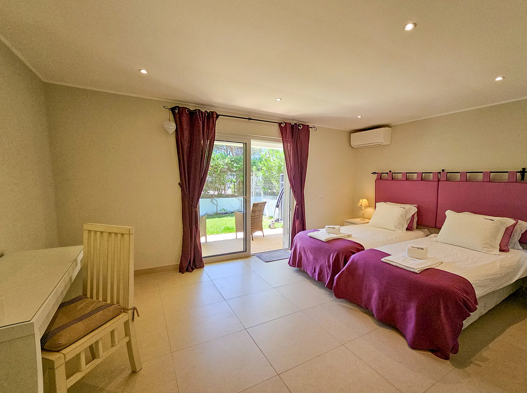 Dormitorio con dos camas y puertas de vidrio que dan a una terraza.