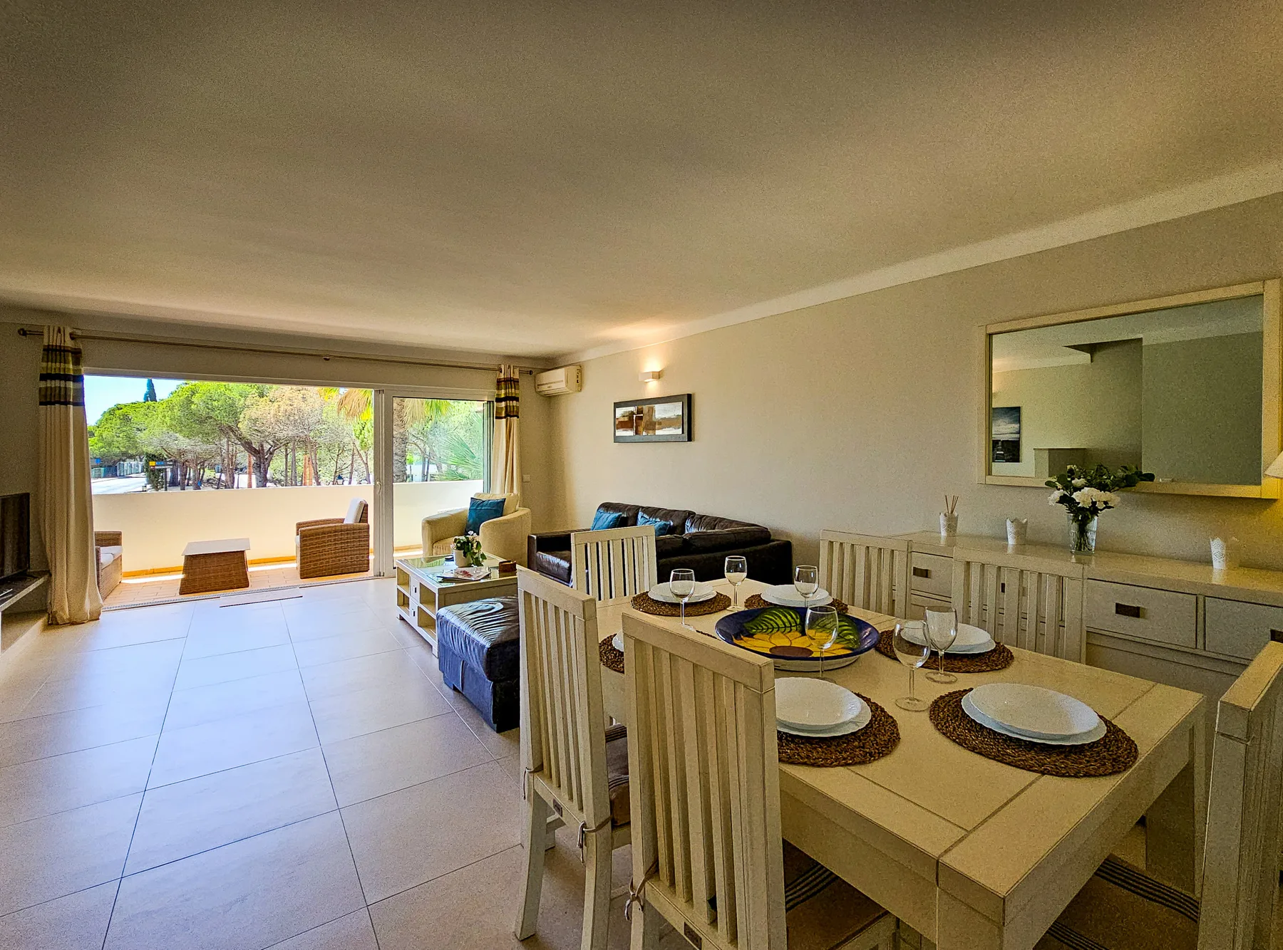 Una zona de comedor y estar da a una terraza a través de amplias puertas correderas de cristal.