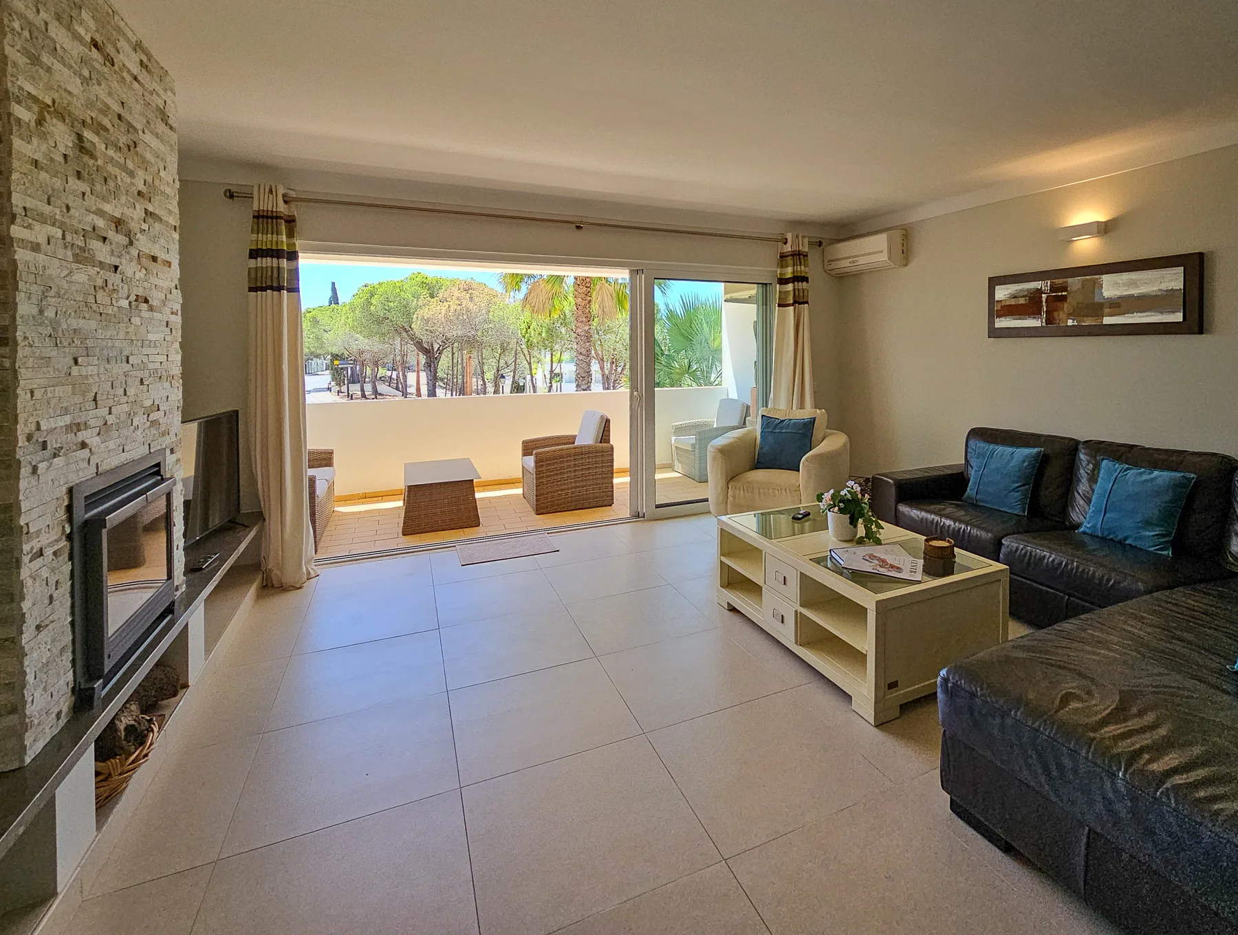 Sala de estar con asientos, una mesa de centro y puertas corredizas de vidrio hacia un patio.