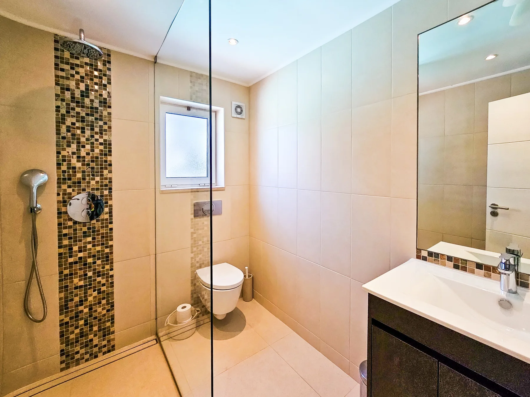 Un baño con azulejos, ducha, inodoro y lavabo.