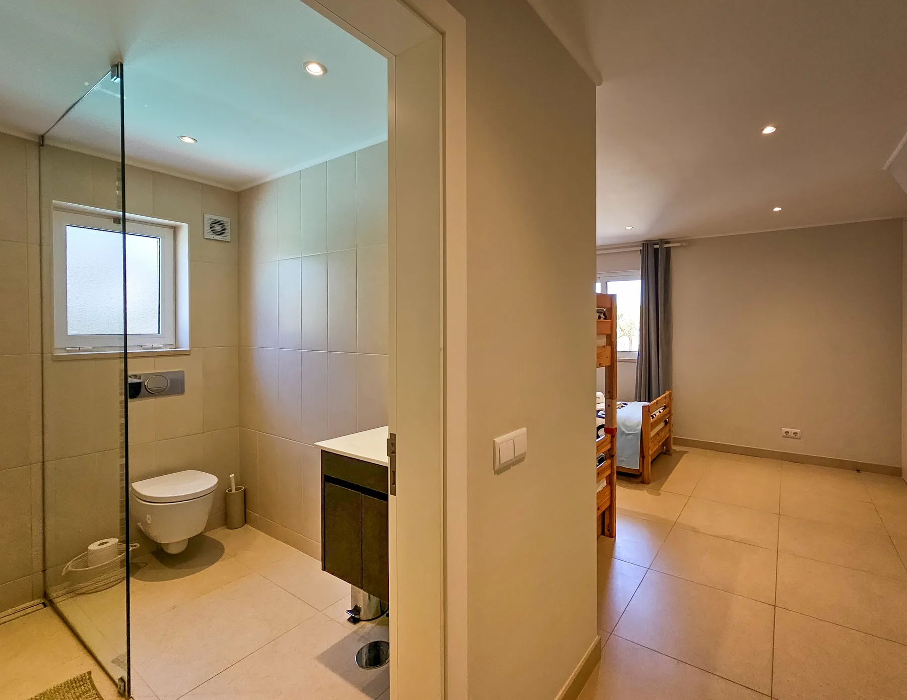 Un baño con ducha de vidrio, inodoro y lavabo montado en la pared.