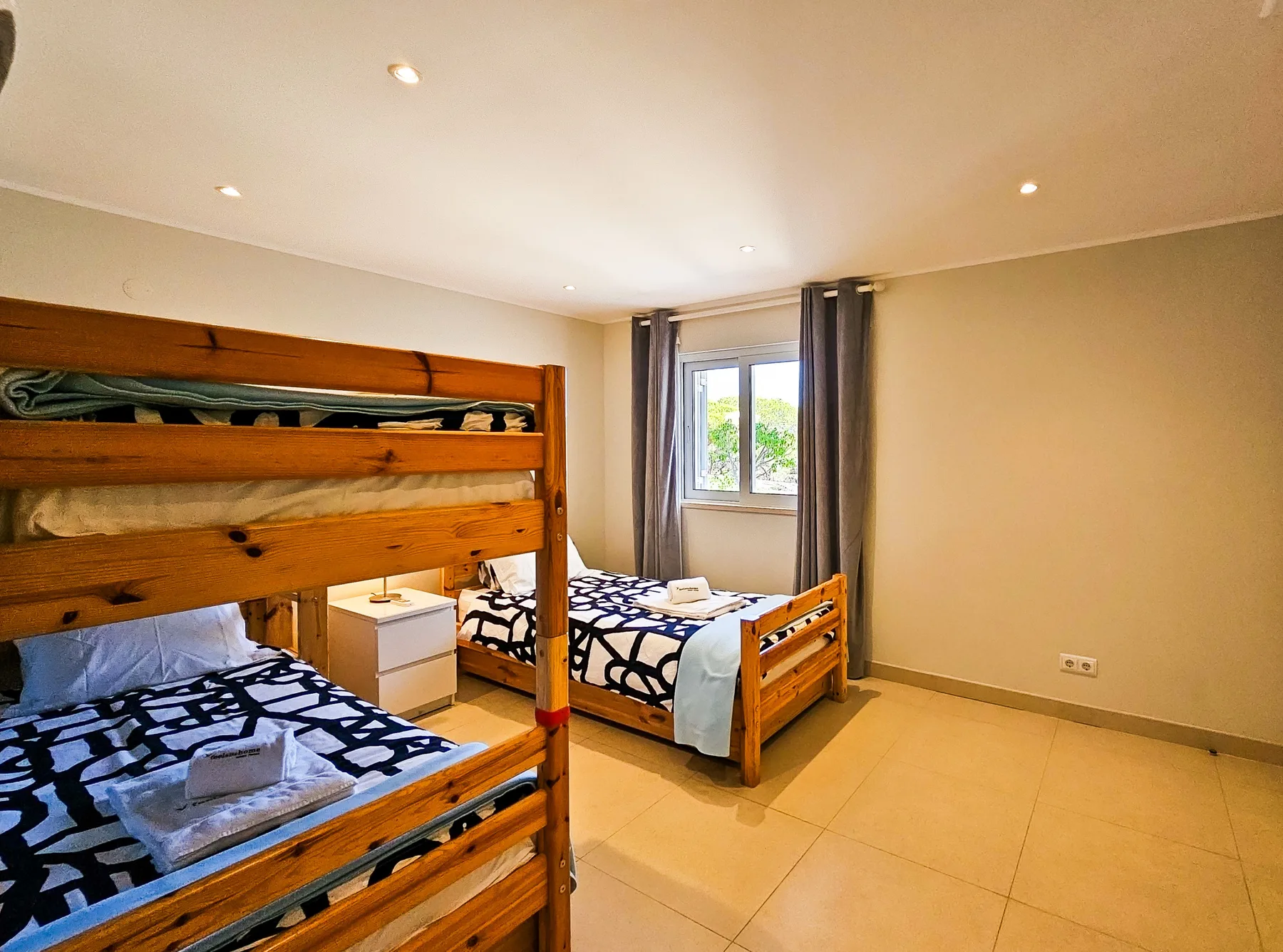 Dormitorio con literas de madera, otra cama y una ventana.