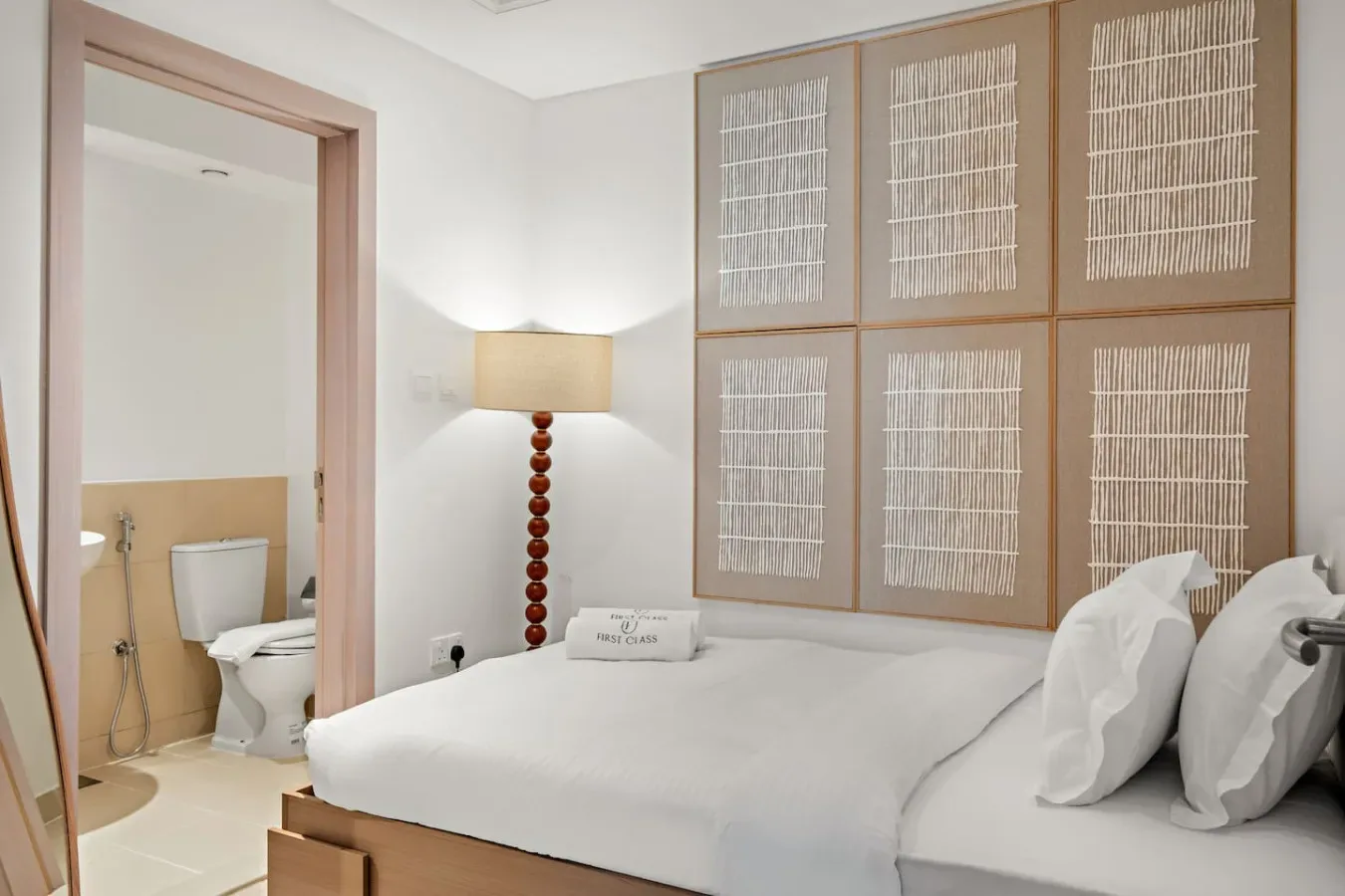 Un dormitorio con una cama bien tendida junto a la entrada del baño.