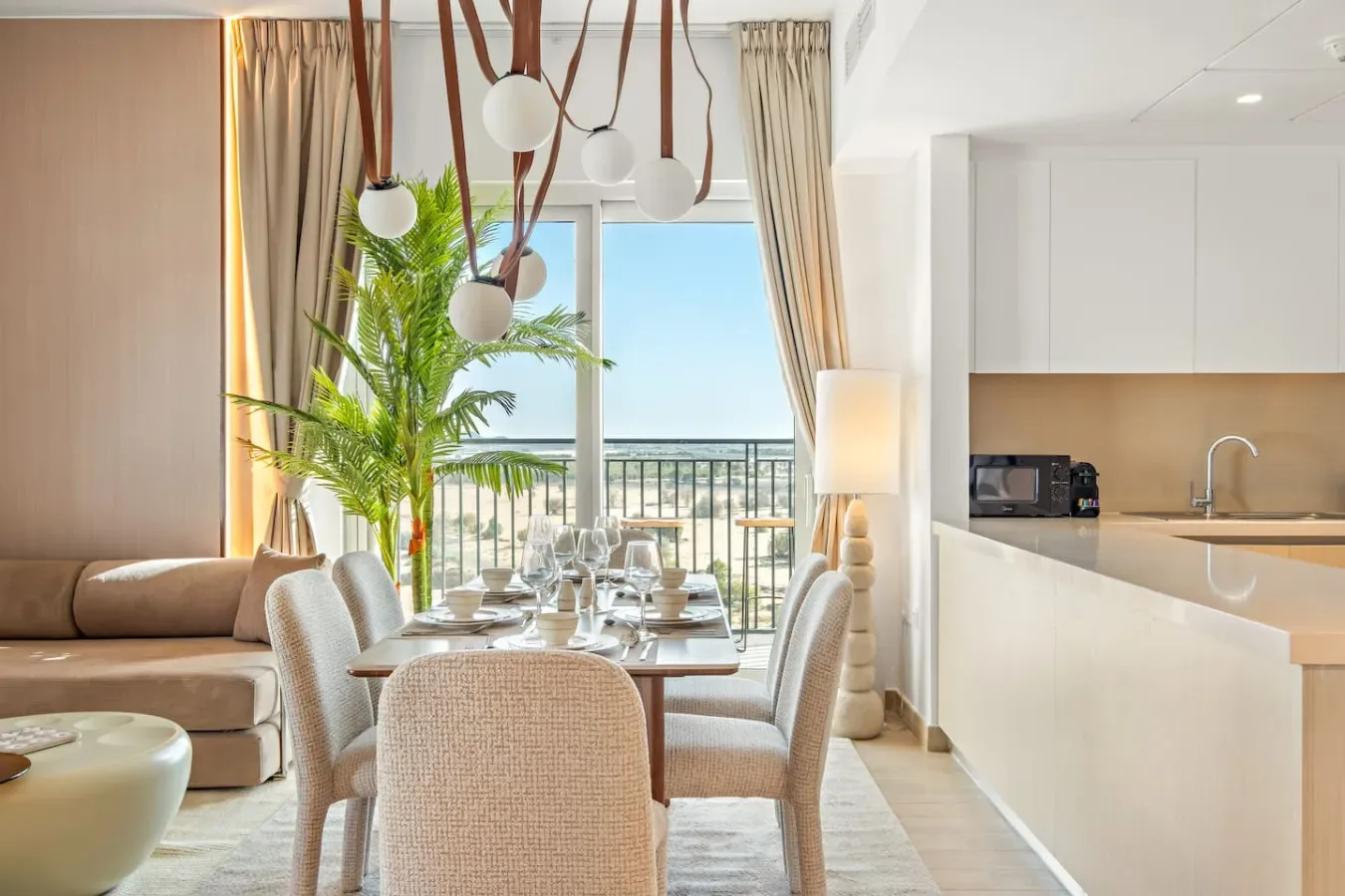 A bright dining area opens onto a balcony, with a table set beside the living space.