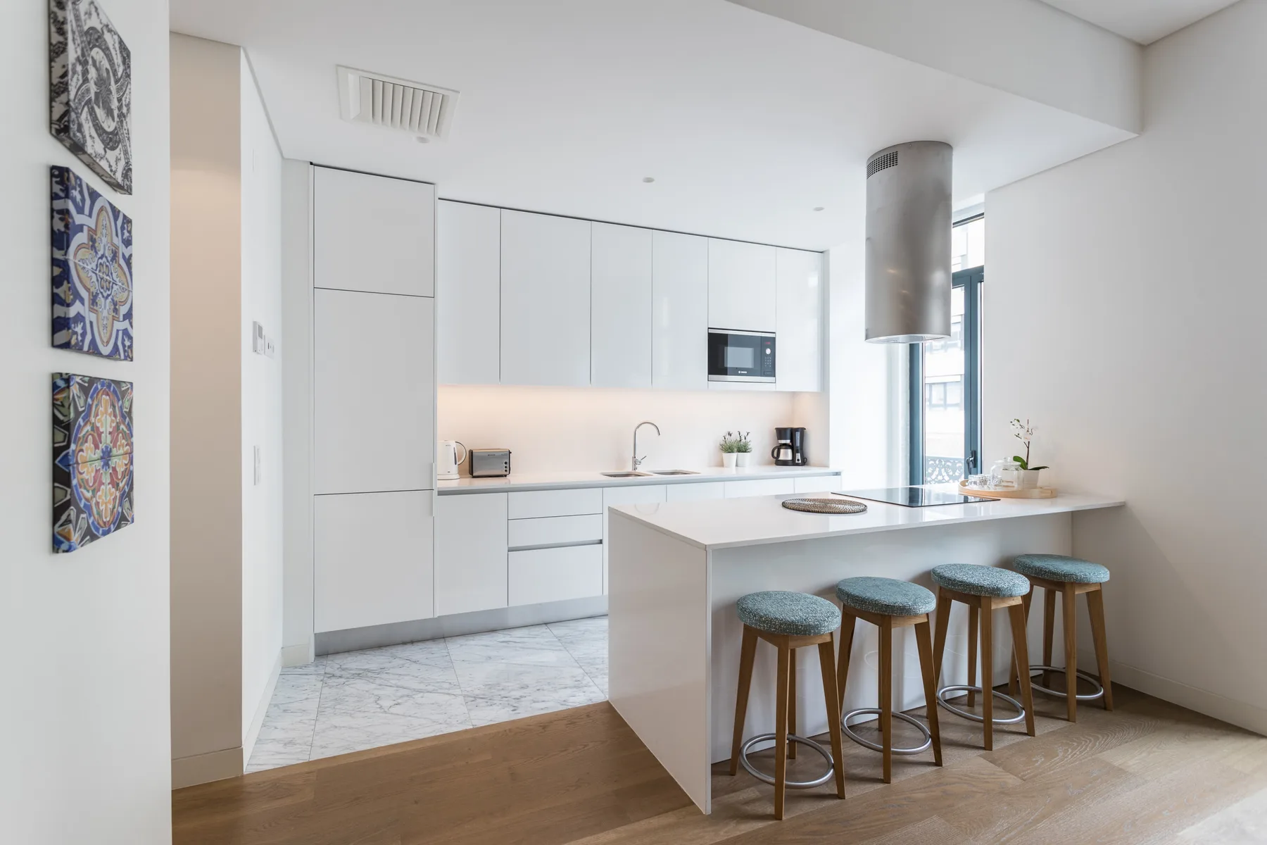 Una cocina moderna y luminosa con una isla blanca y taburetes.