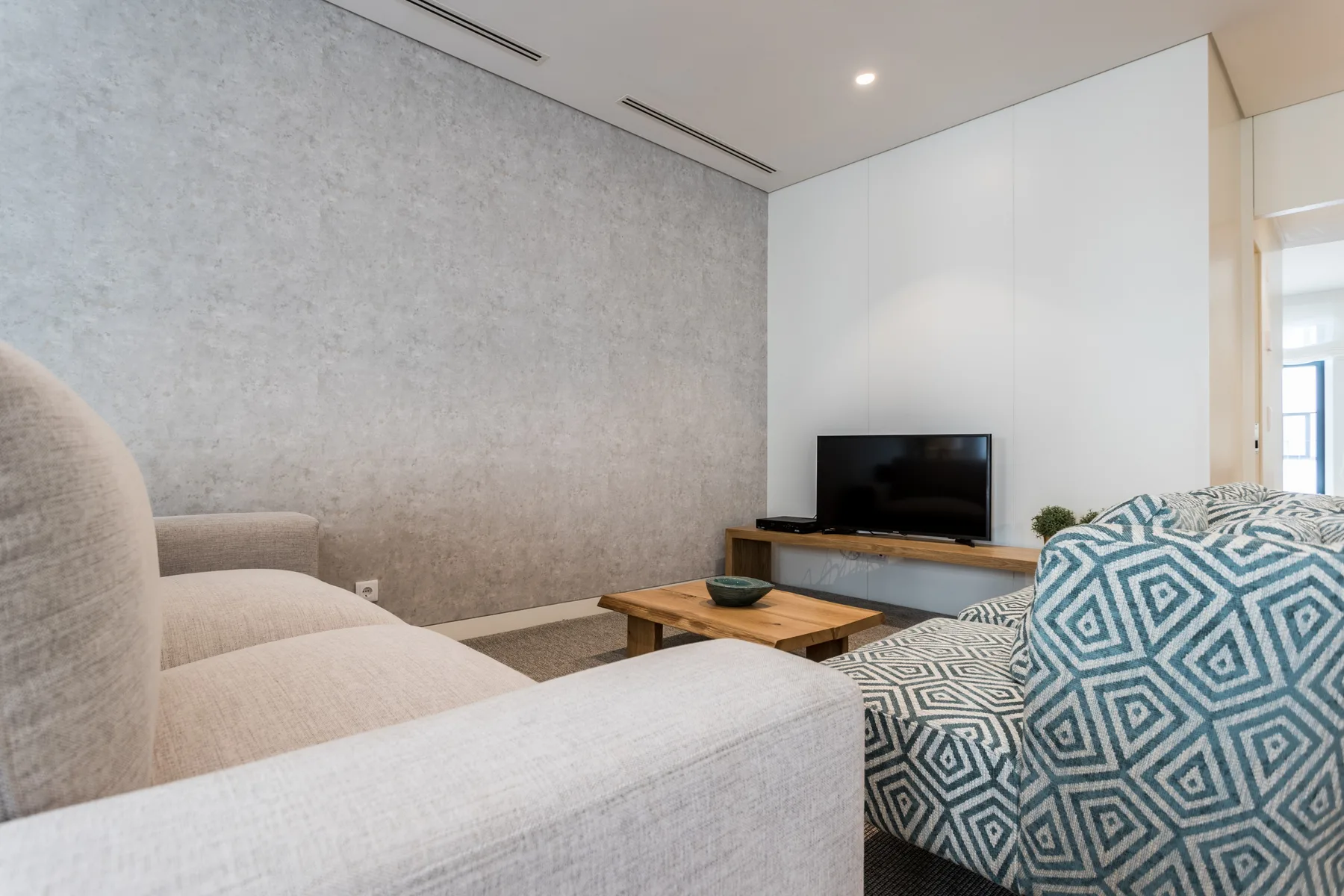 Sala de estar con asientos, un televisor y una mesa de centro de madera.