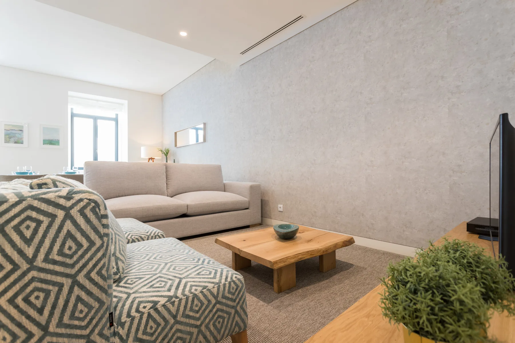 Sala de estar con asientos, una mesa de centro de madera y un televisor.