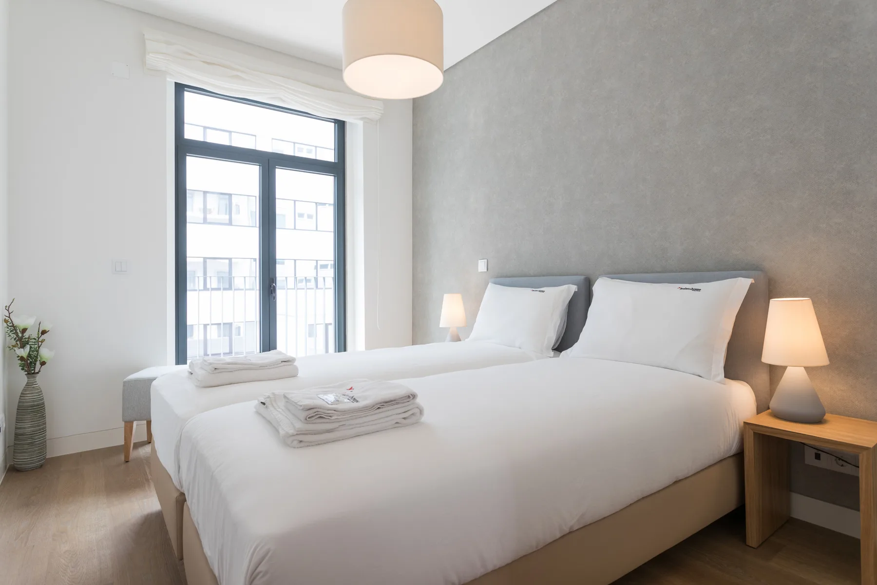 Un dormitorio luminoso con una cama grande junto a una ventana alta.