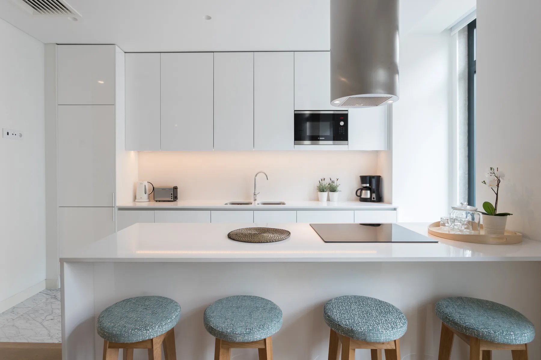 Una cocina moderna con una barra larga y taburetes azules.