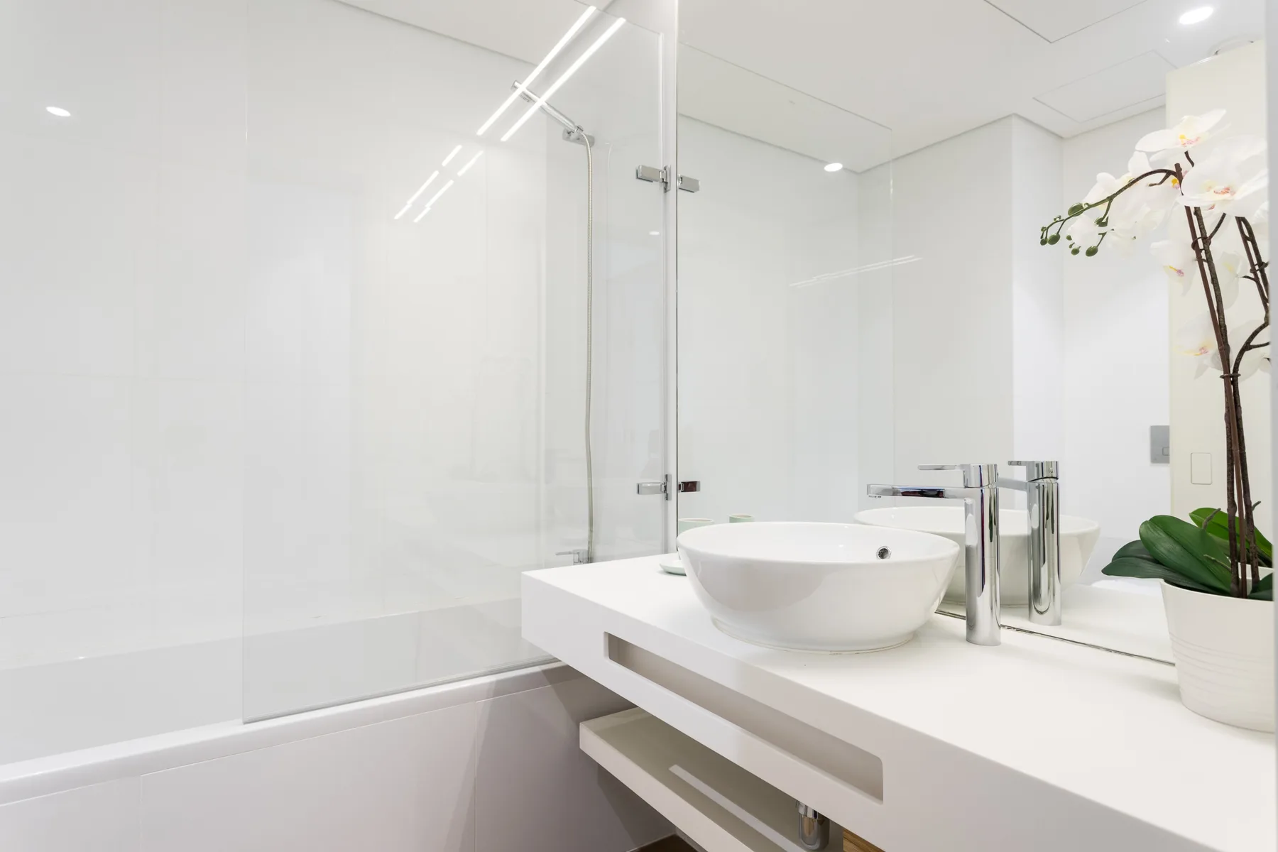 Un baño luminoso con una bañera blanca y un lavabo sobre un mueble suspendido.