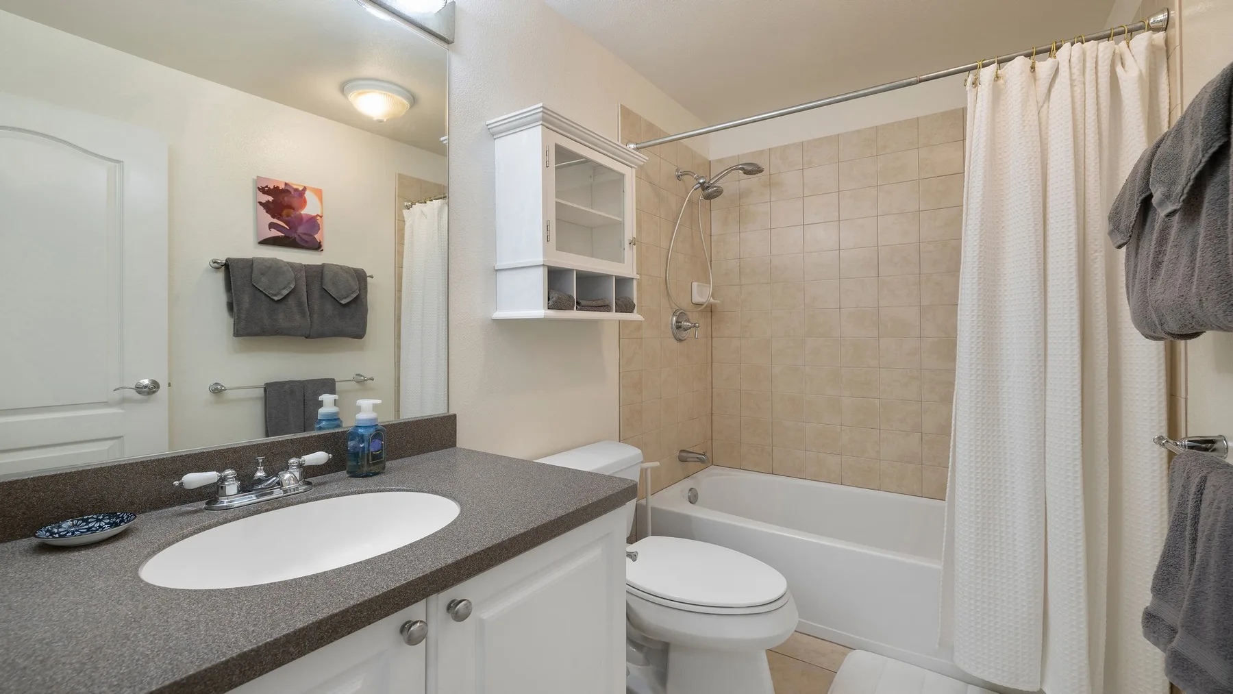 Un baño con lavabo, inodoro y bañera detrás de una cortina de ducha.