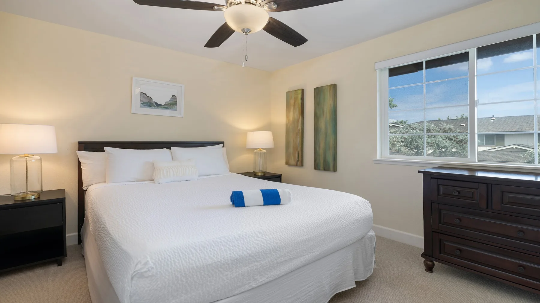 Un dormitorio luminoso con una cama bien arreglada y una ventana grande.