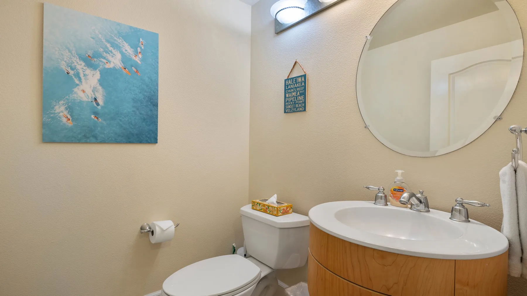 Un baño con un espejo redondo sobre el lavabo y un inodoro.
