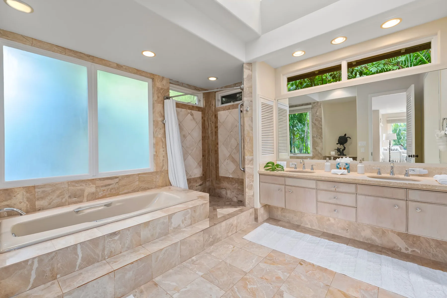A spacious bathroom with a built-in tub, glass shower, and long vanity.