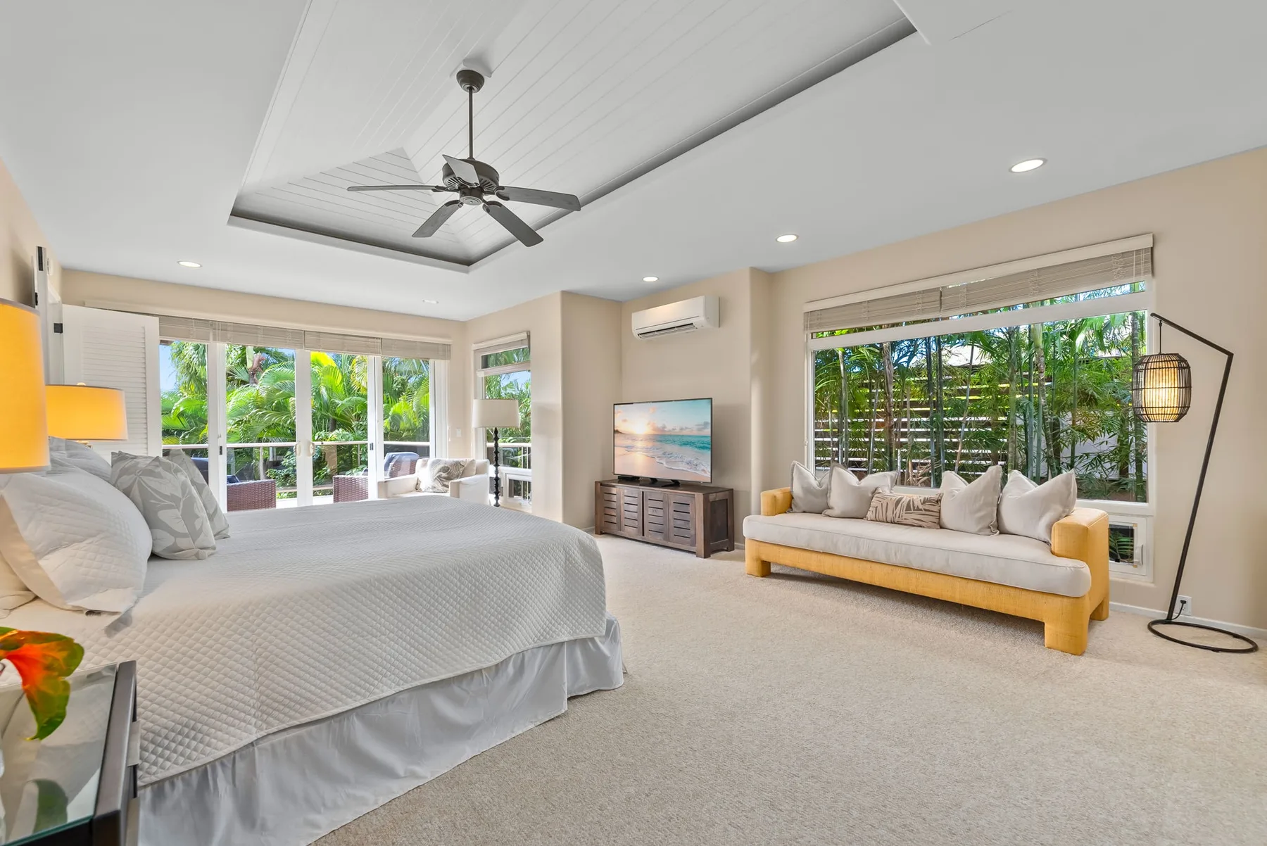A bright bedroom with a large bed and a seating area beside wide windows.