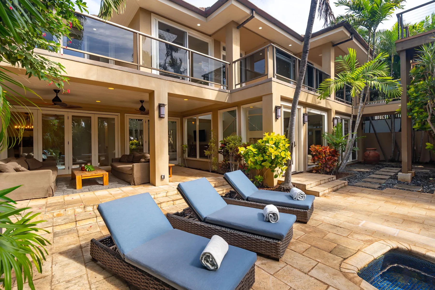 A sunny patio with blue lounge seating beside a modern house.