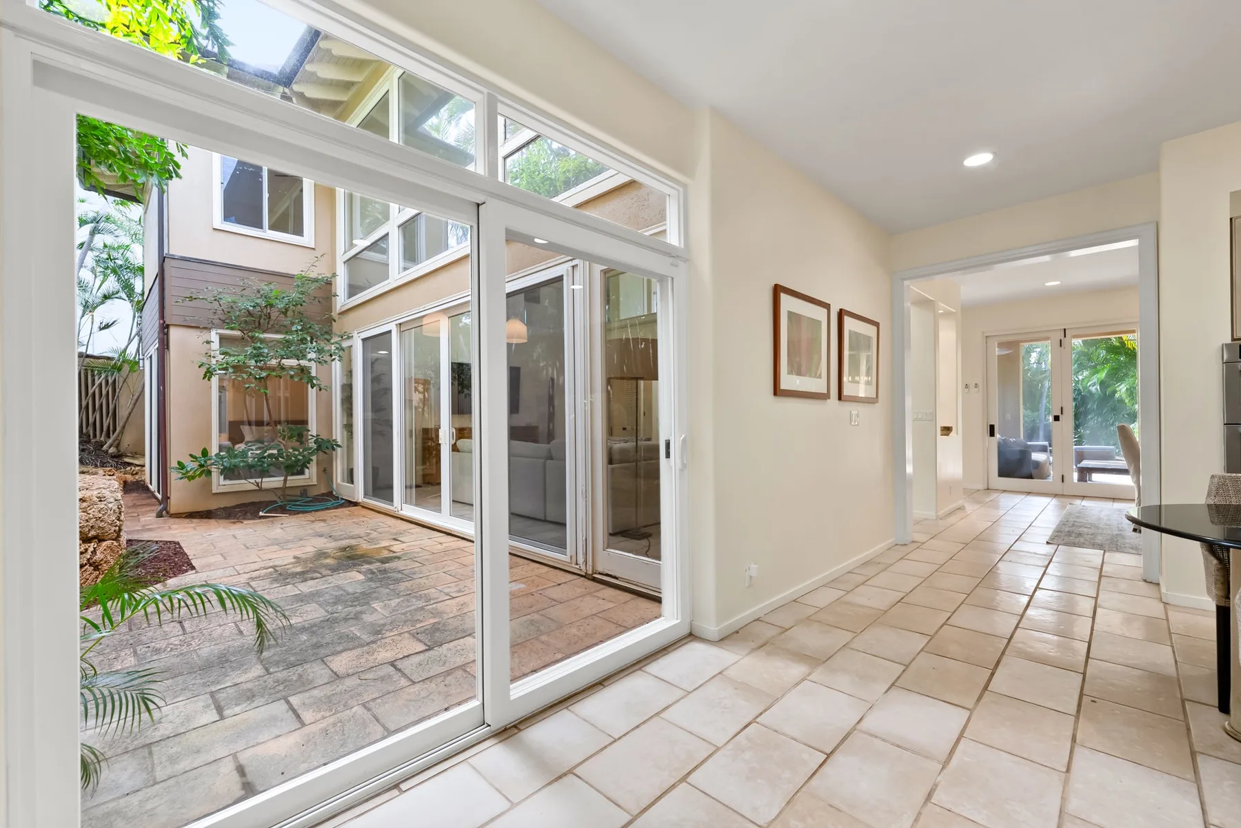 A bright tiled interior opens through glass doors onto a paved courtyard.