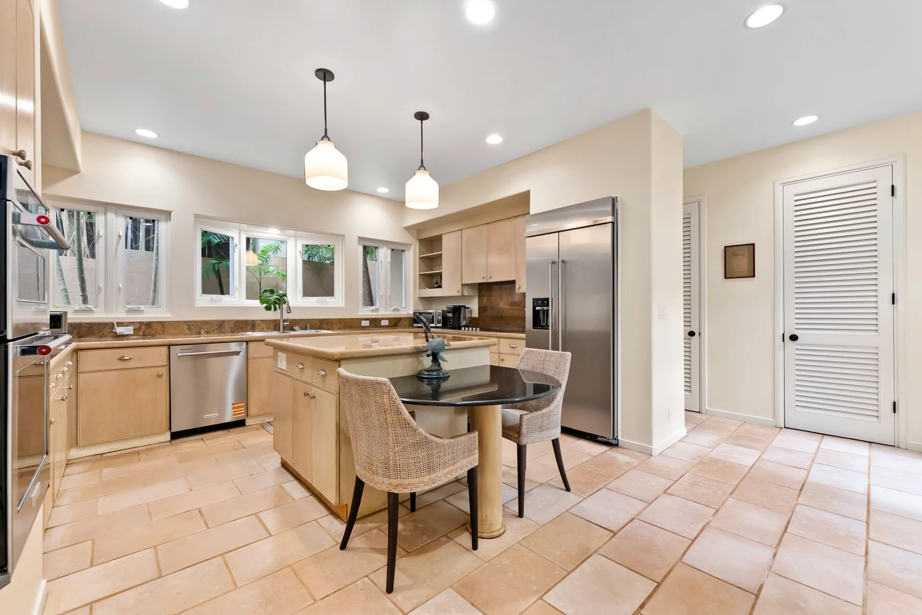 A bright kitchen with light wood cabinets, a central island, and stainless steel appliances.