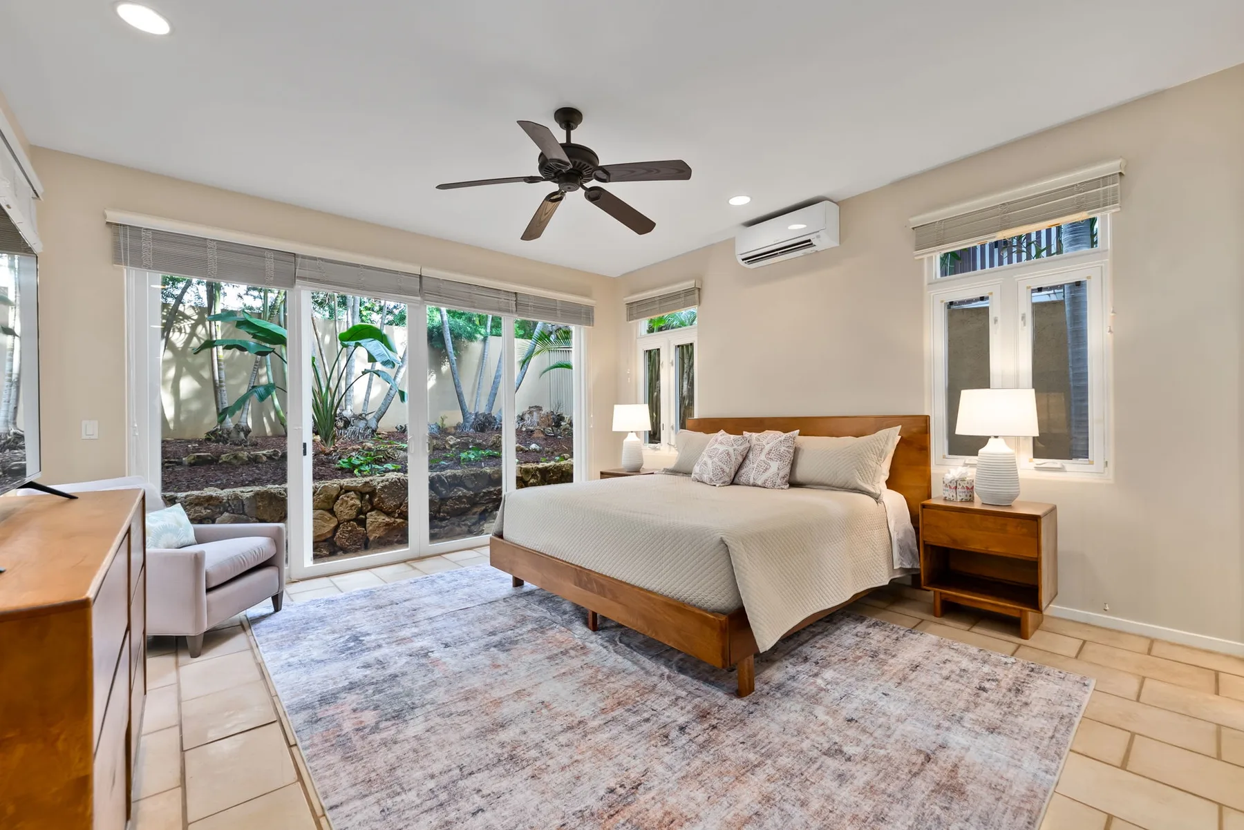 A bedroom with a bed, bedside tables, and sliding glass doors opening to a garden.