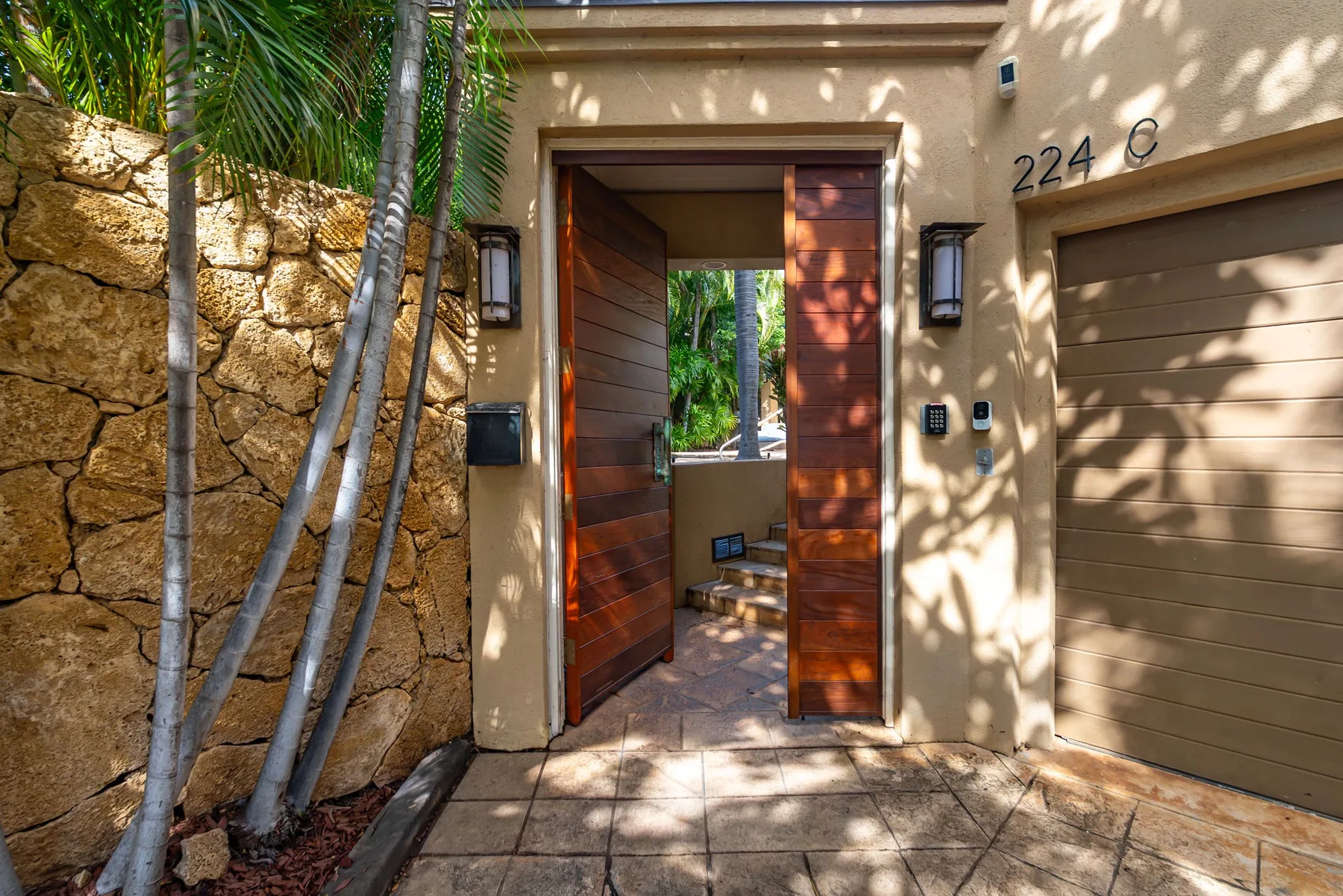 An exterior entryway with an open wooden door beside a garage.