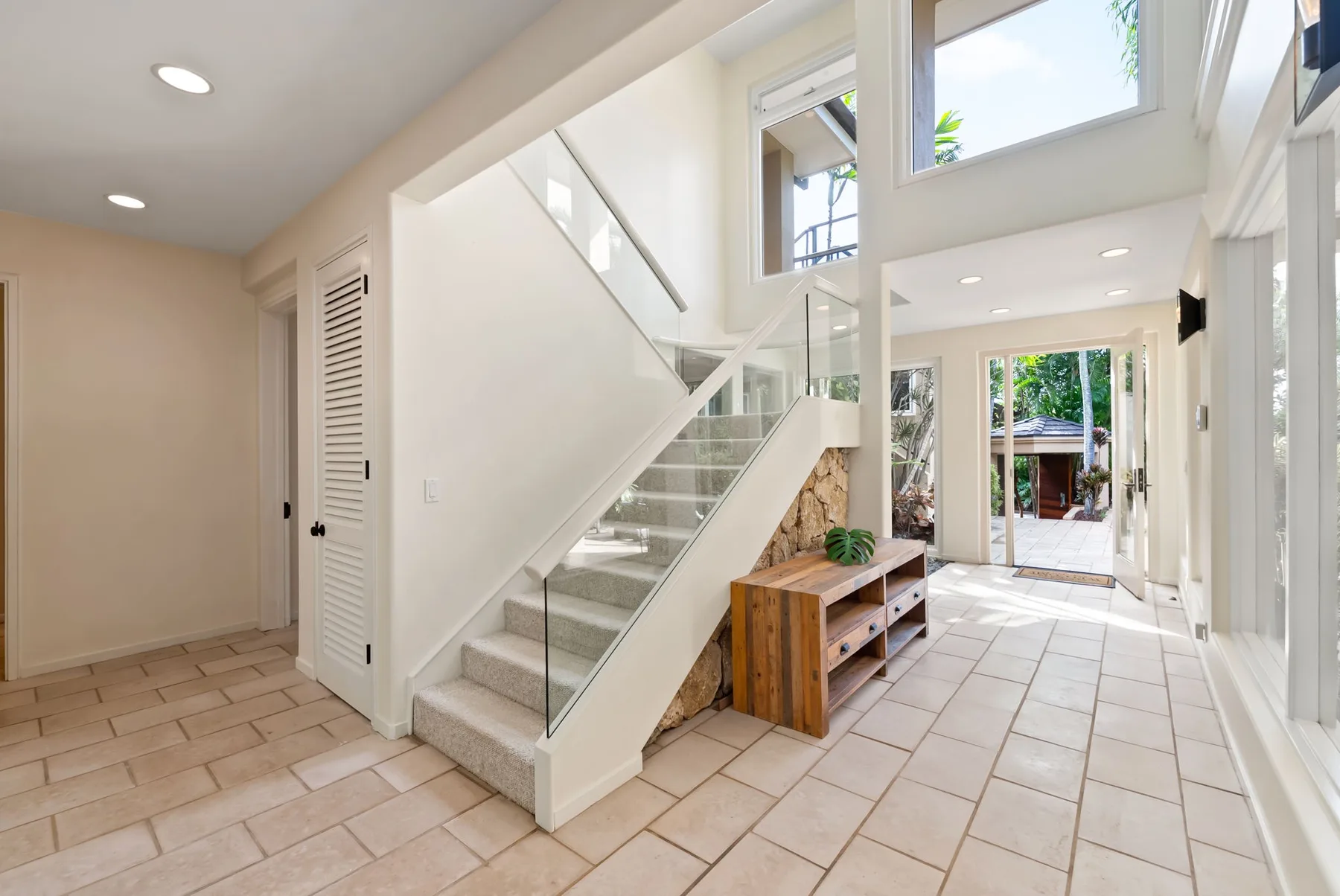 A bright interior hallway with a staircase and large windows.