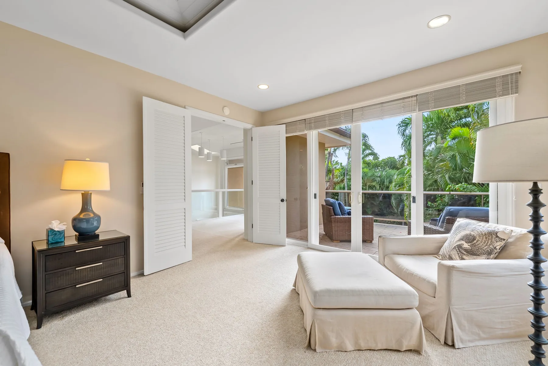 A bright living room with seating beside large windows overlooking greenery.