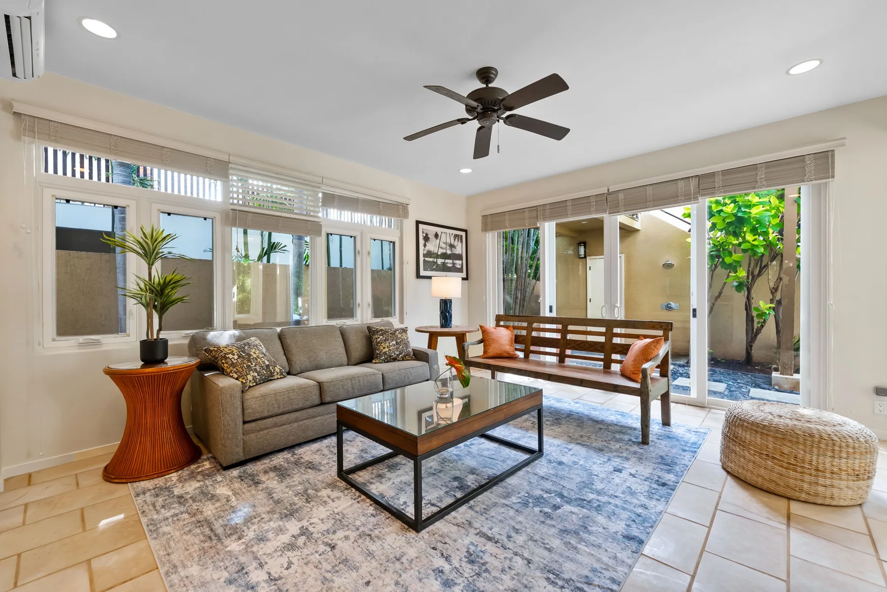 A bright living room with seating, a coffee table, and glass doors opening to a patio.