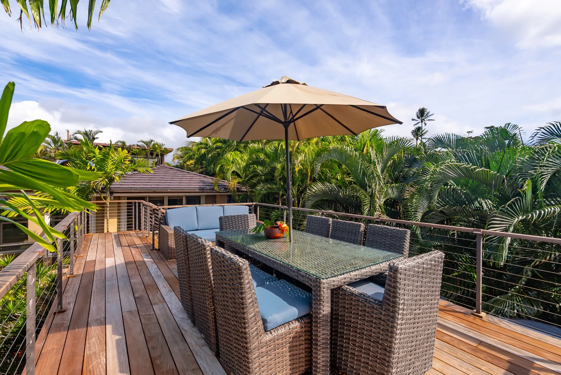 An outdoor dining area on a wooden deck sits beneath a large umbrella.