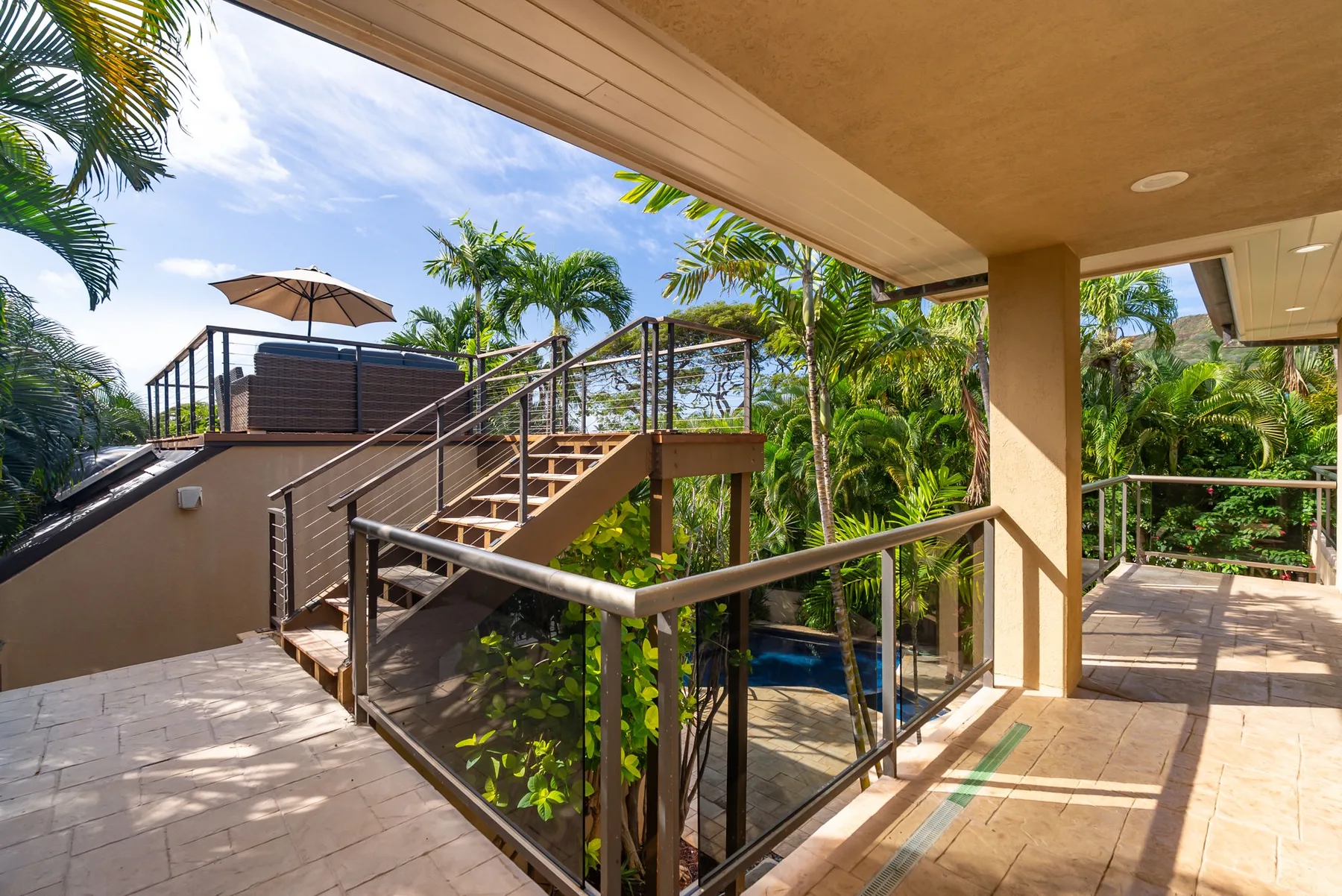 An outdoor patio and staircase overlook a lush garden.
