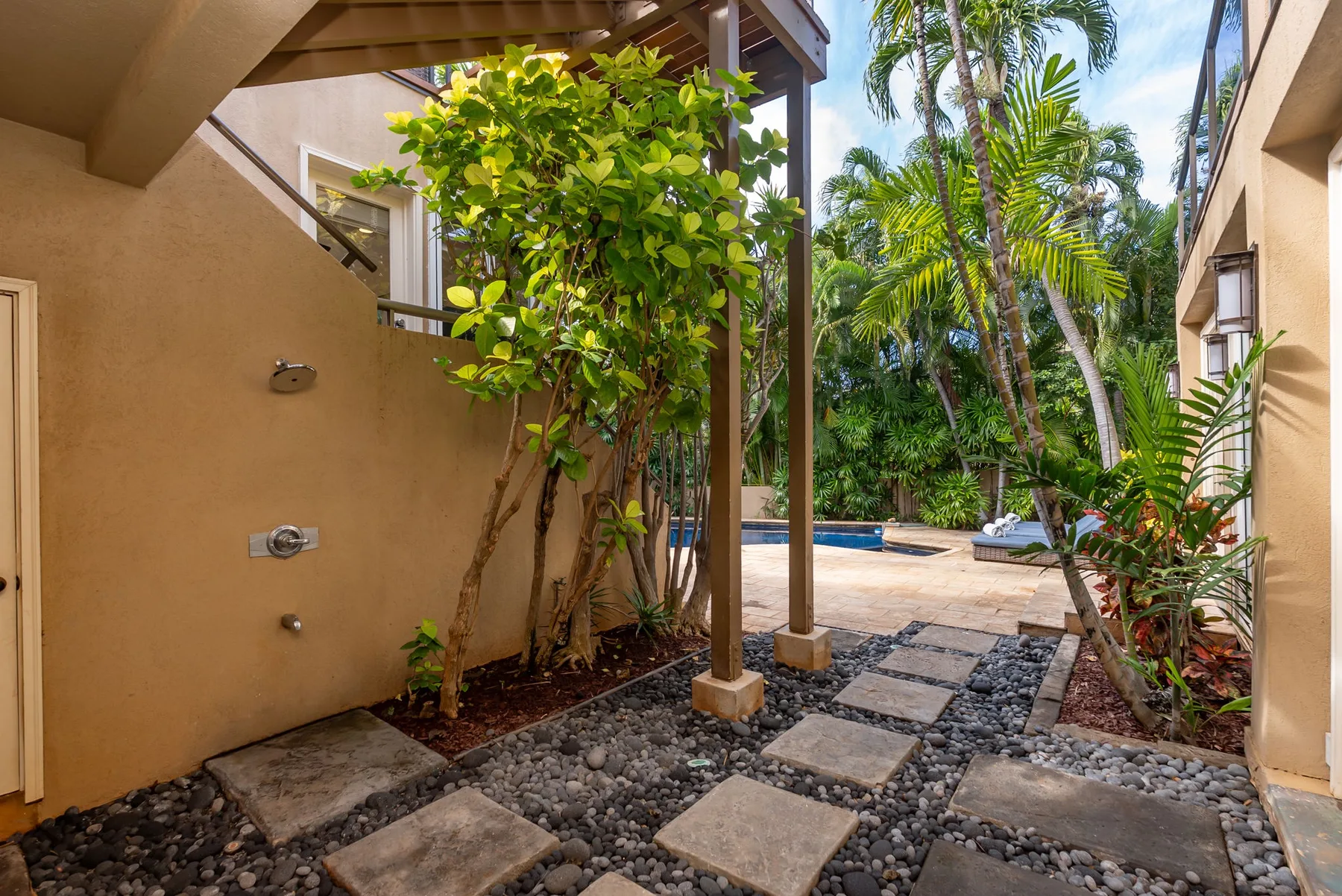 An outdoor shower area opens onto a landscaped patio with a swimming pool.