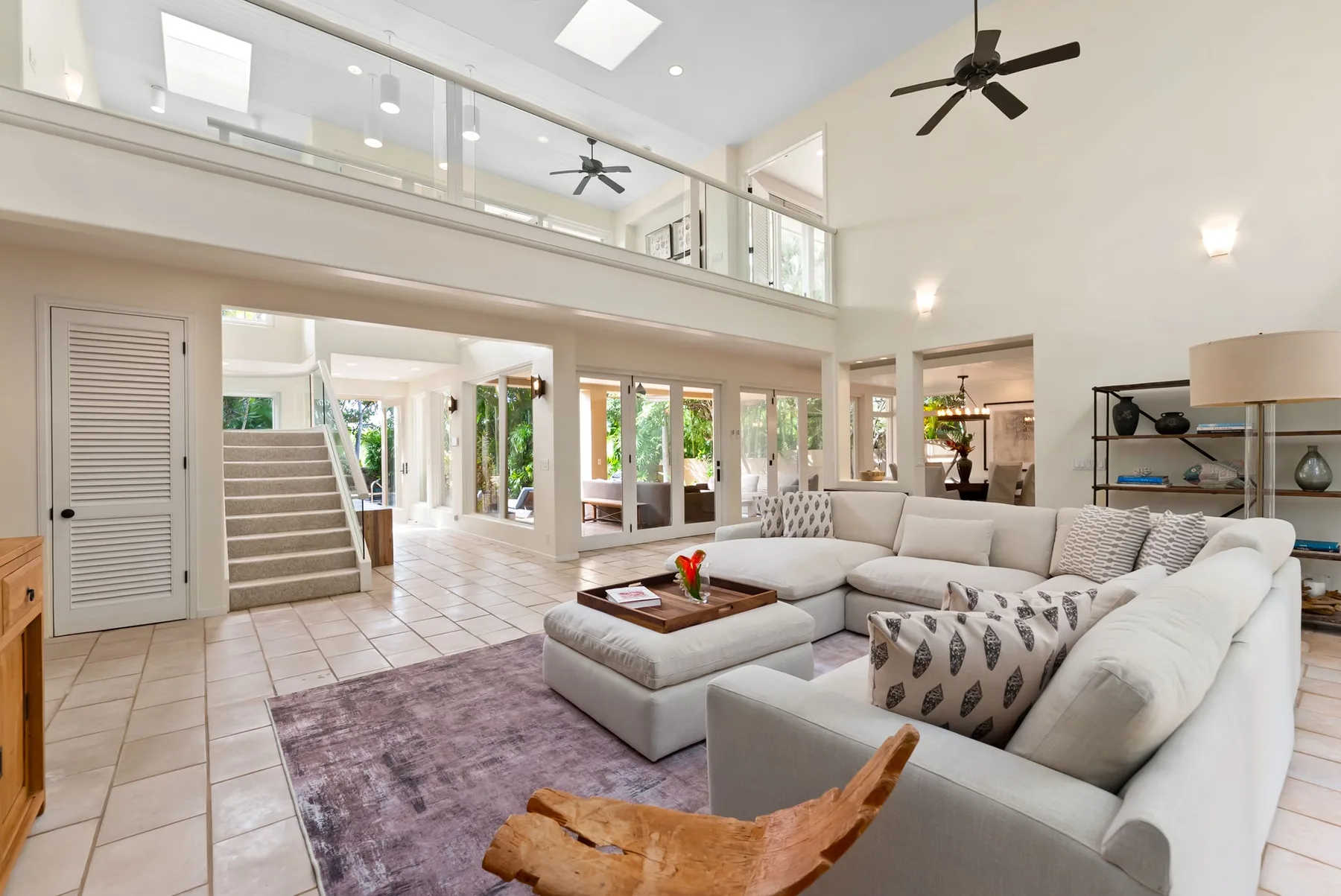 A bright open-plan living room with pale seating and an upper-level gallery.