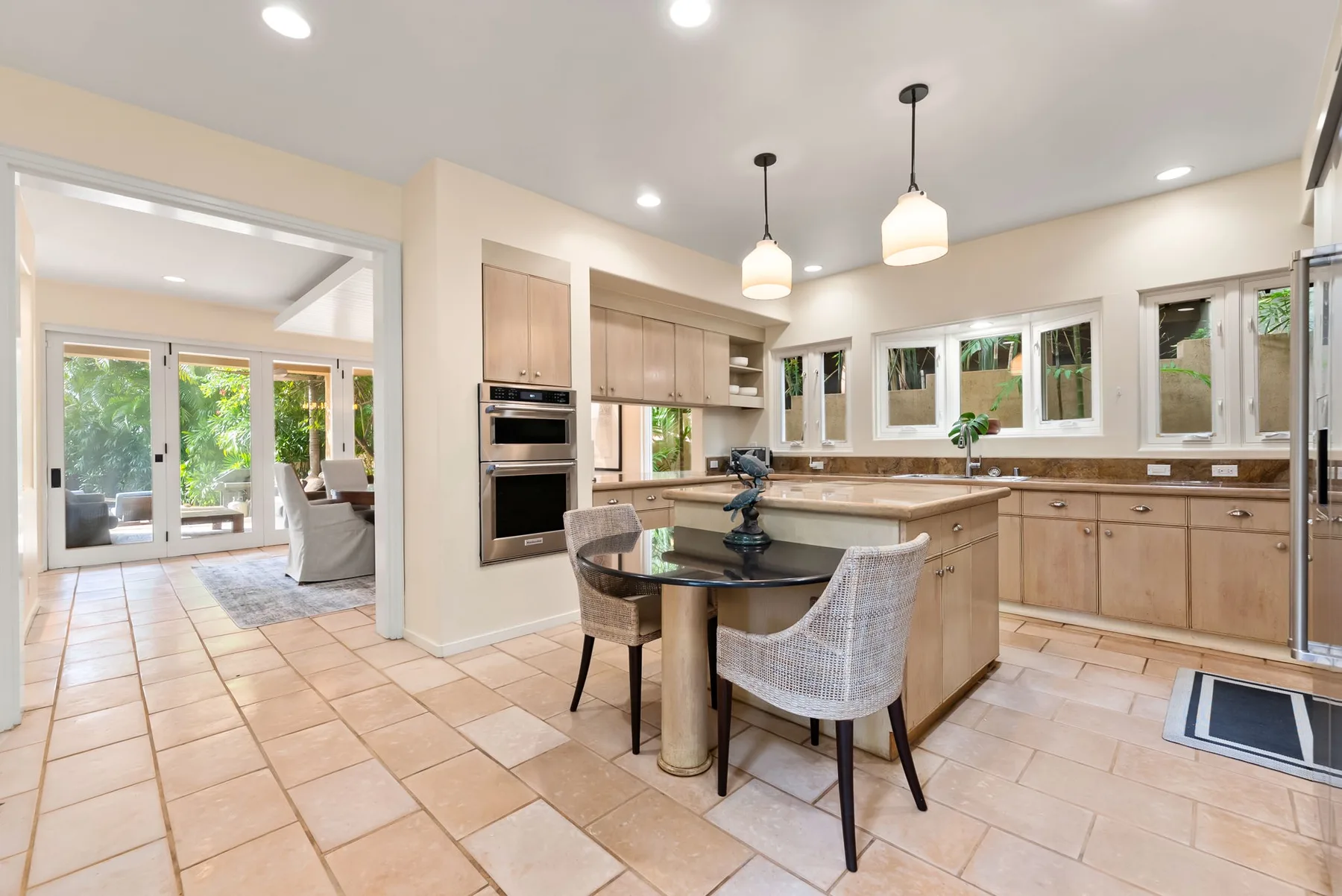 A bright kitchen with a central island and dining chairs.