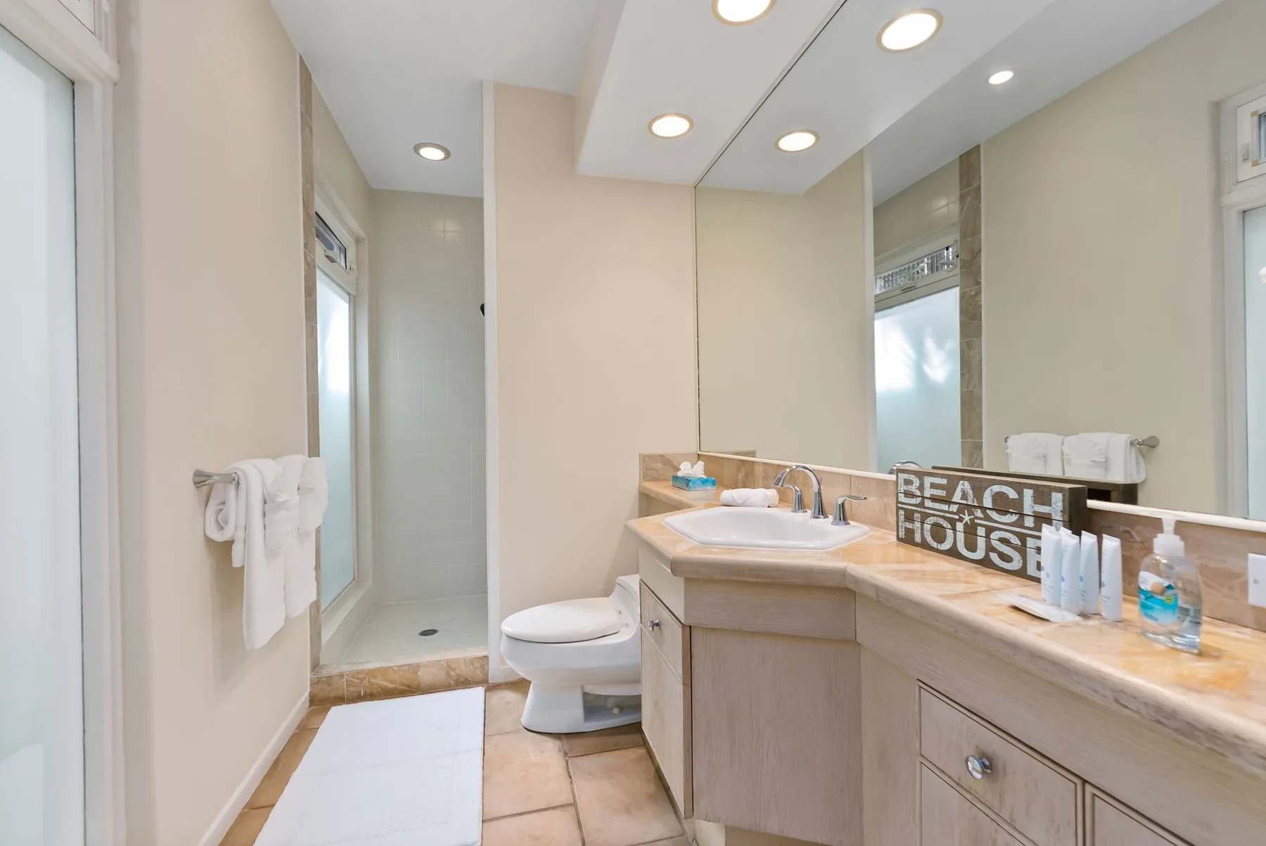 A bathroom with a long vanity, large mirror, and shower area.