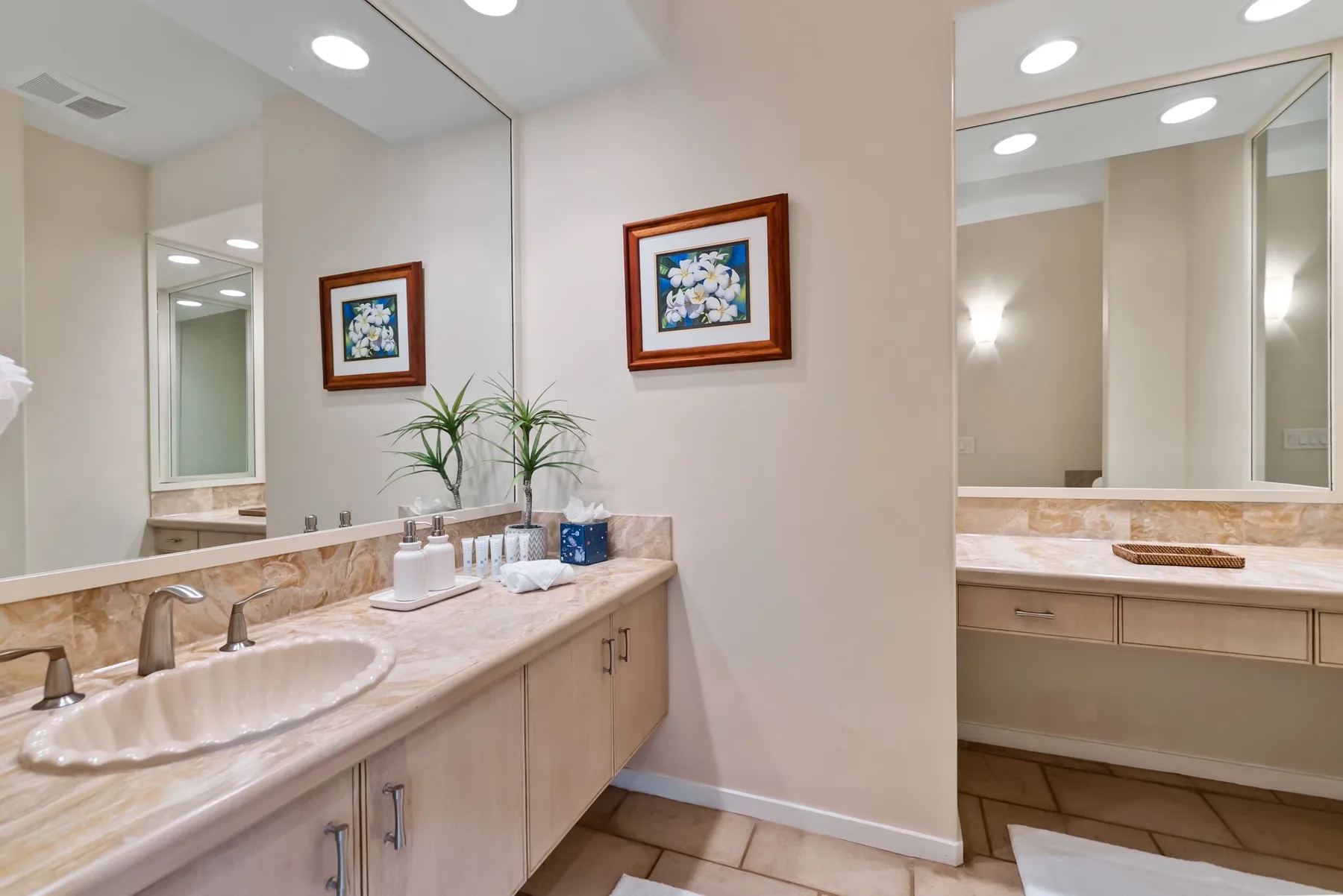 A bright bathroom with a long vanity, sinks, and large mirrors.
