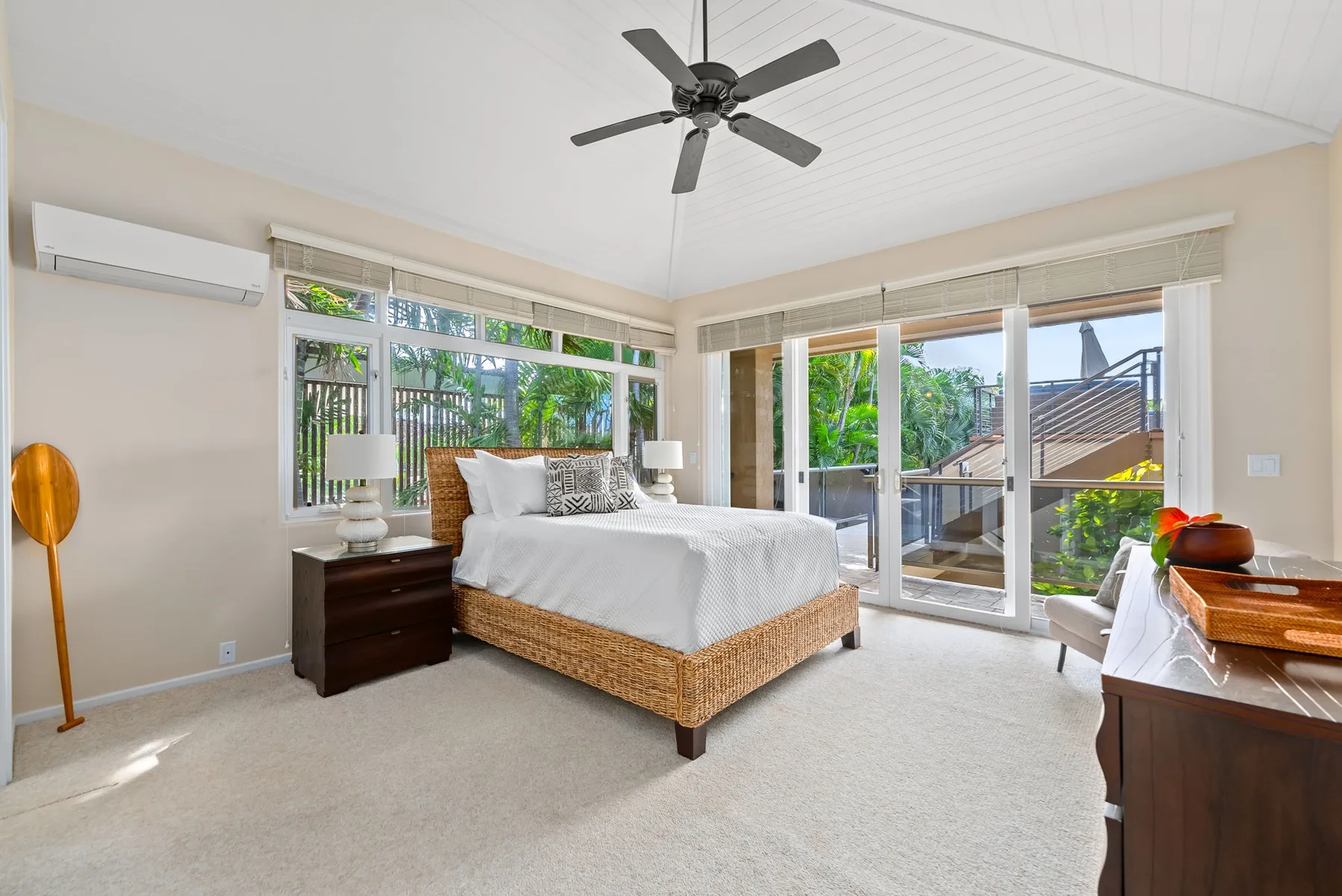 A bright bedroom with a bed beside large windows and glass doors.