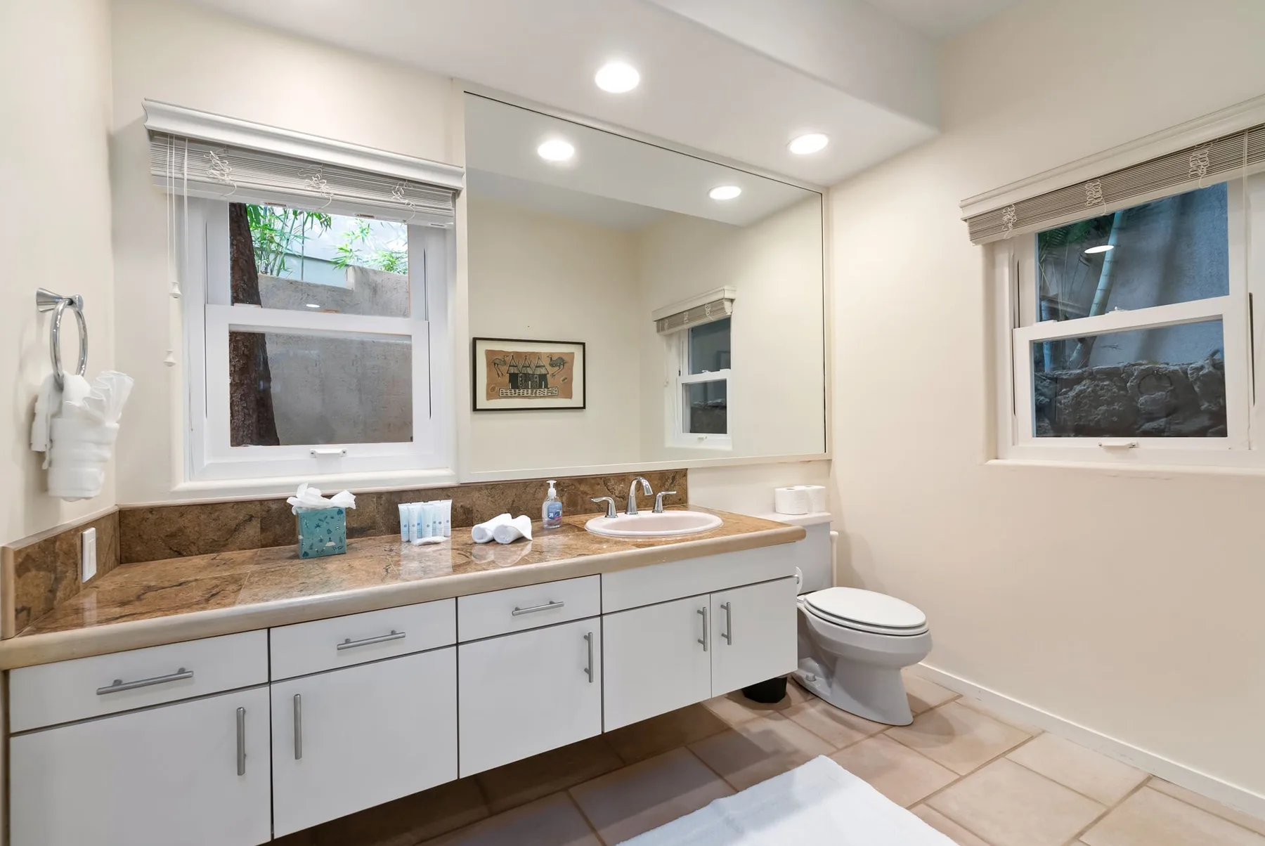 A bathroom with a long vanity, mirror, and toilet.