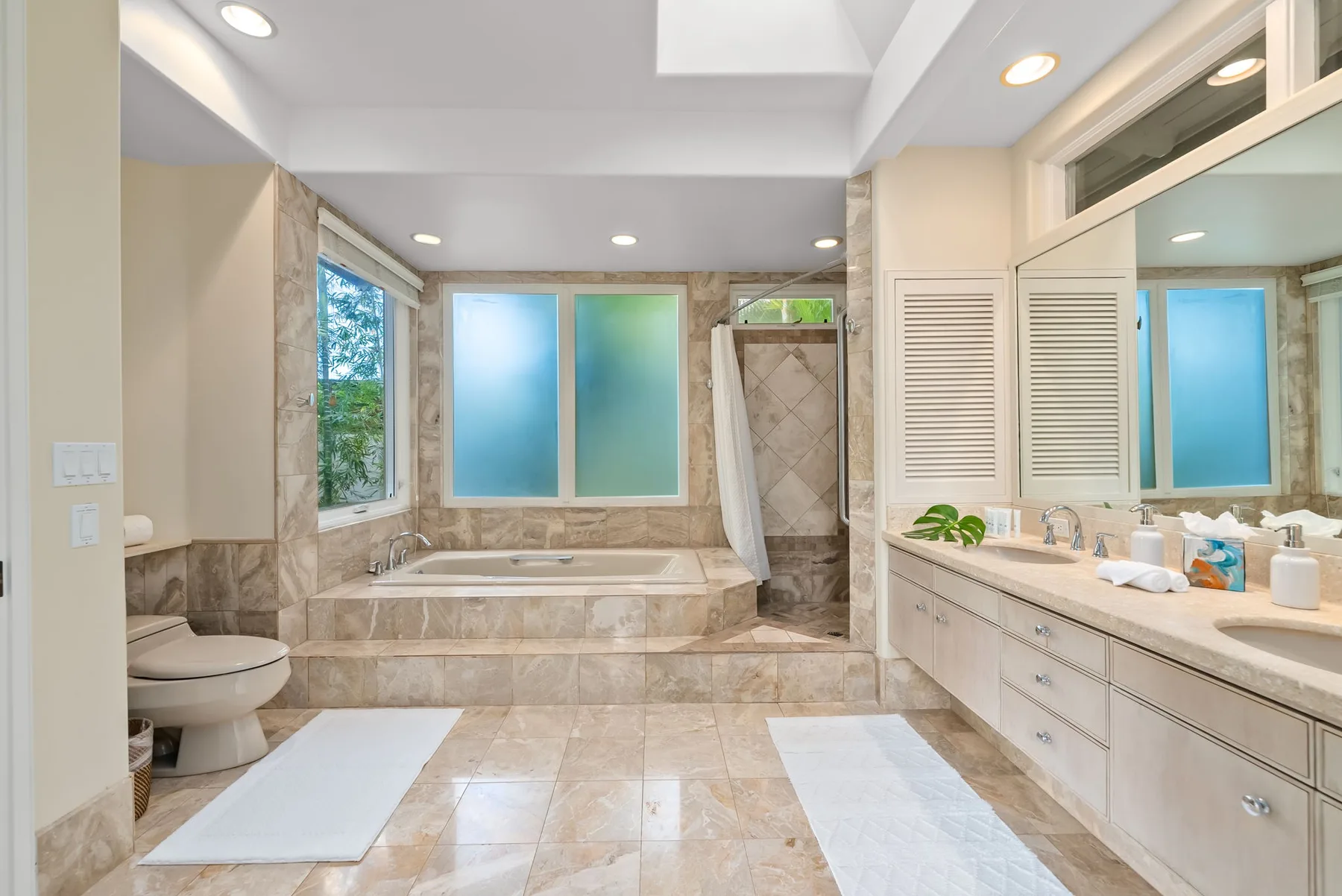 A spacious bathroom with a bathtub, shower, and long vanity.