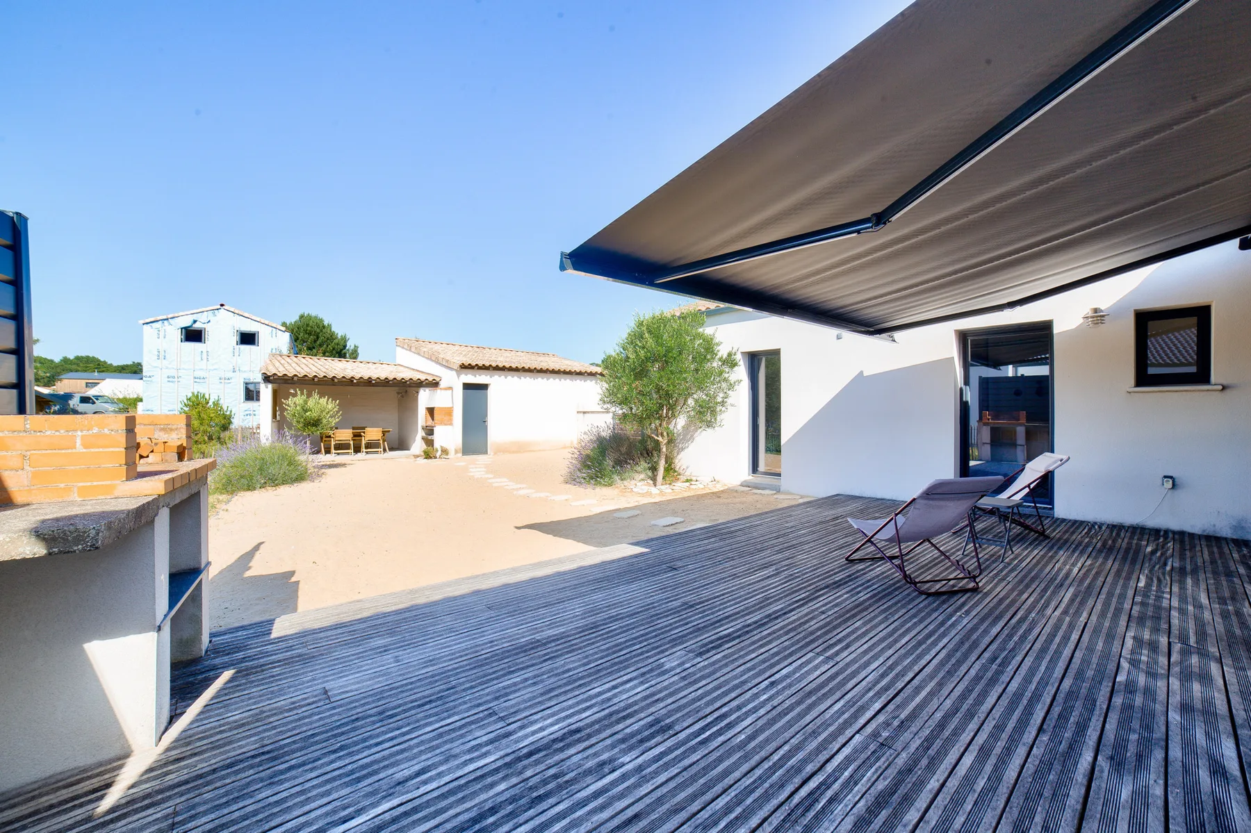An outdoor patio with a retractable awning and seating beside a courtyard.
