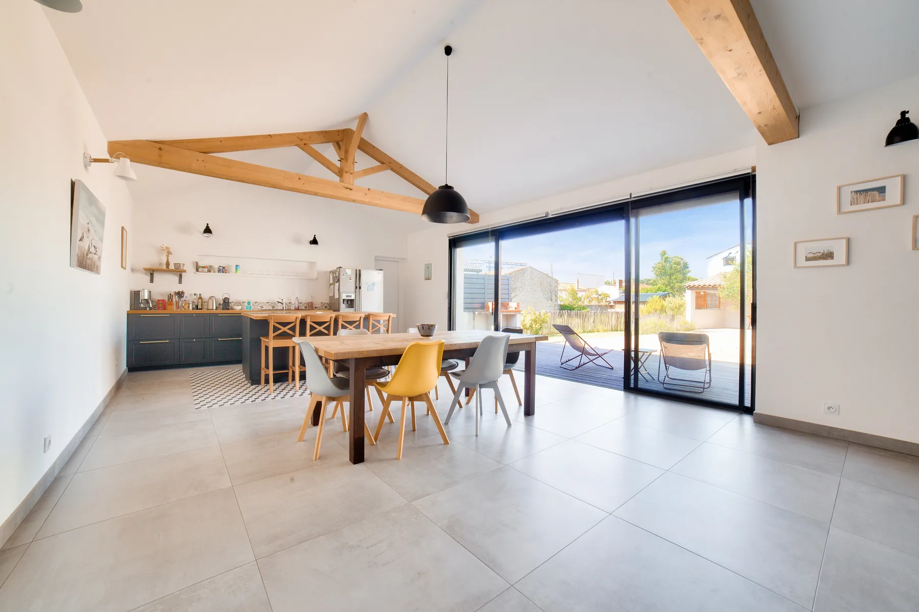 Open-plan living and dining area with a kitchen and large glass doors.