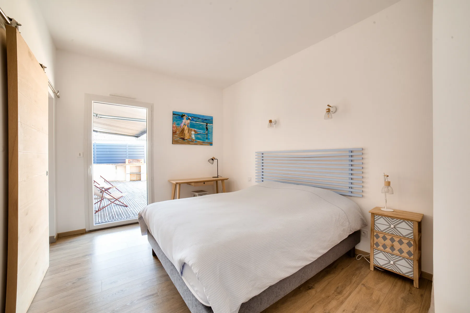 A bedroom with a bed, bedside tables, and a window.