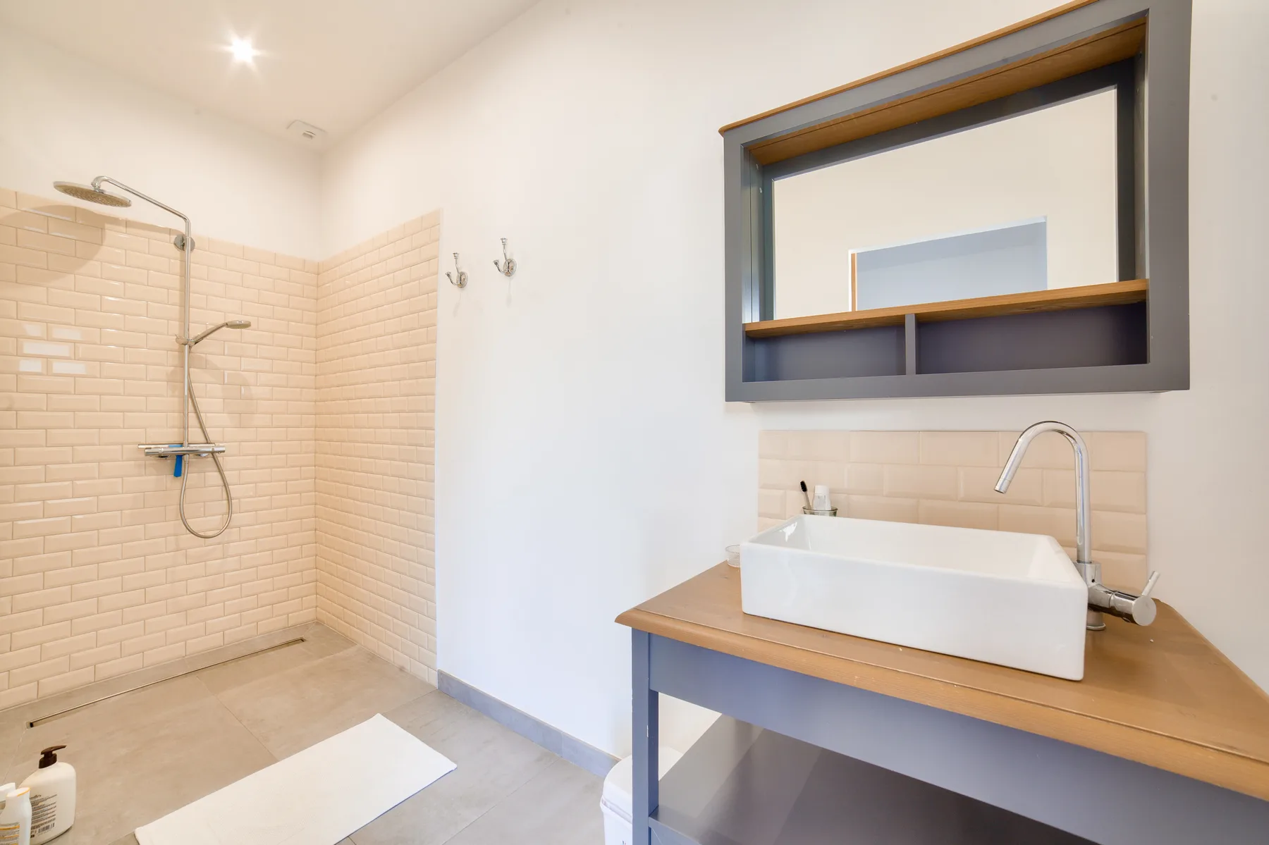 A bathroom with a walk-in shower and a sink beneath a wall mirror.