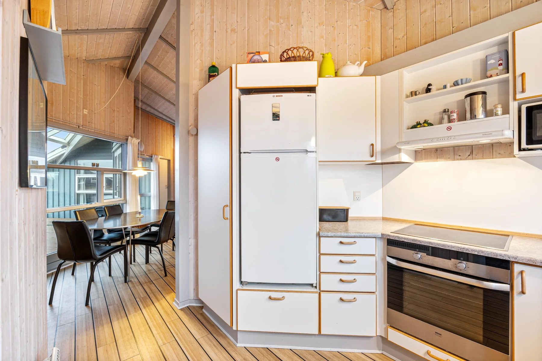 Una cocina luminosa con gabinetes blancos y un comedor junto a grandes ventanas.