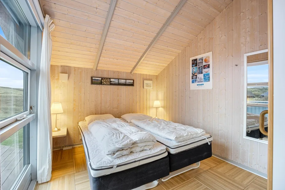 Un dormitorio luminoso con dos camas bajo un techo de madera inclinado.
