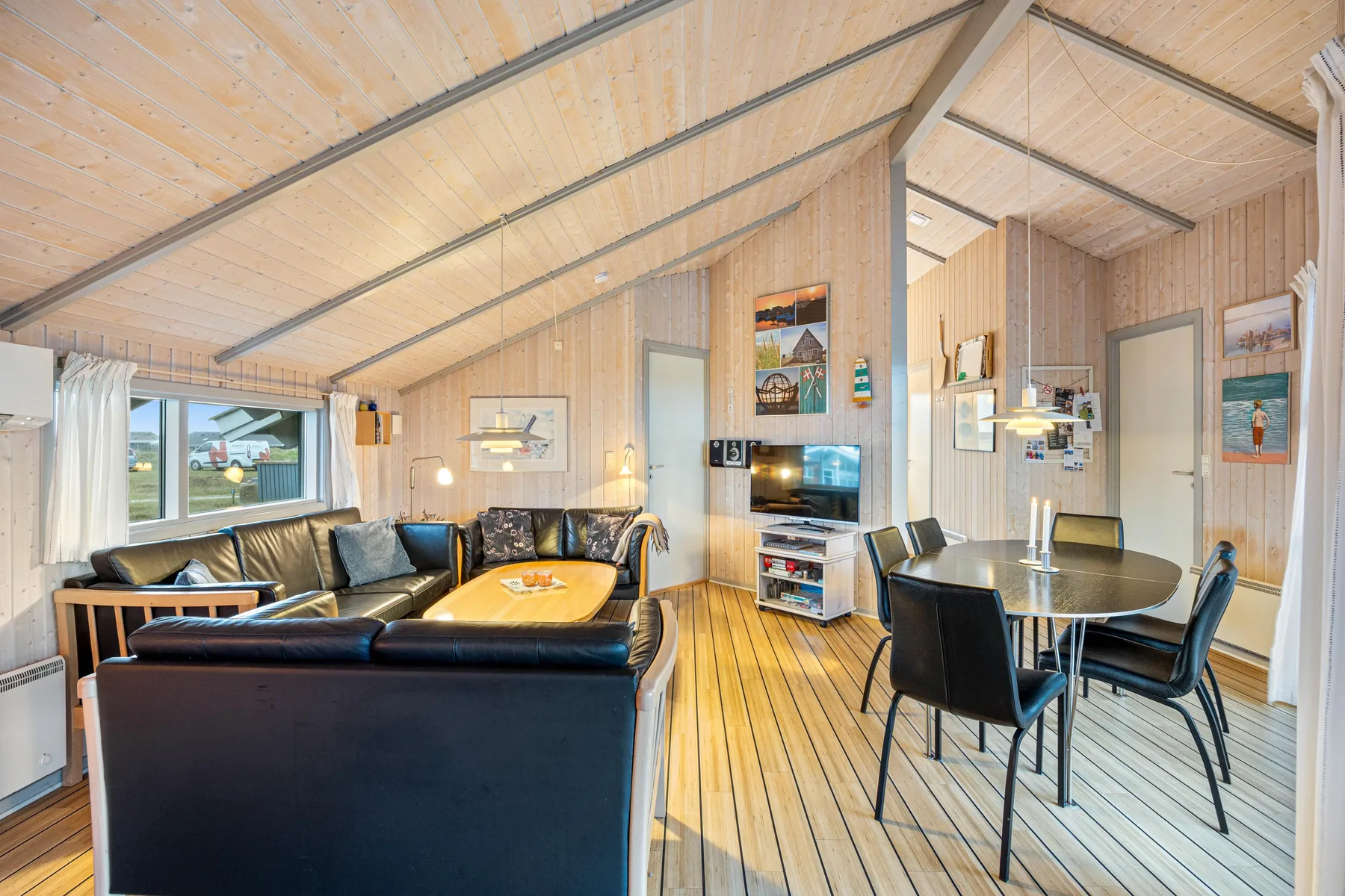 Una sala y comedor revestidos de madera, con asientos, una mesa y un televisor.