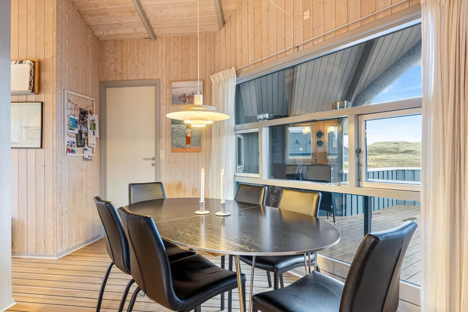 Un comedor con una mesa y sillas junto a grandes ventanas.